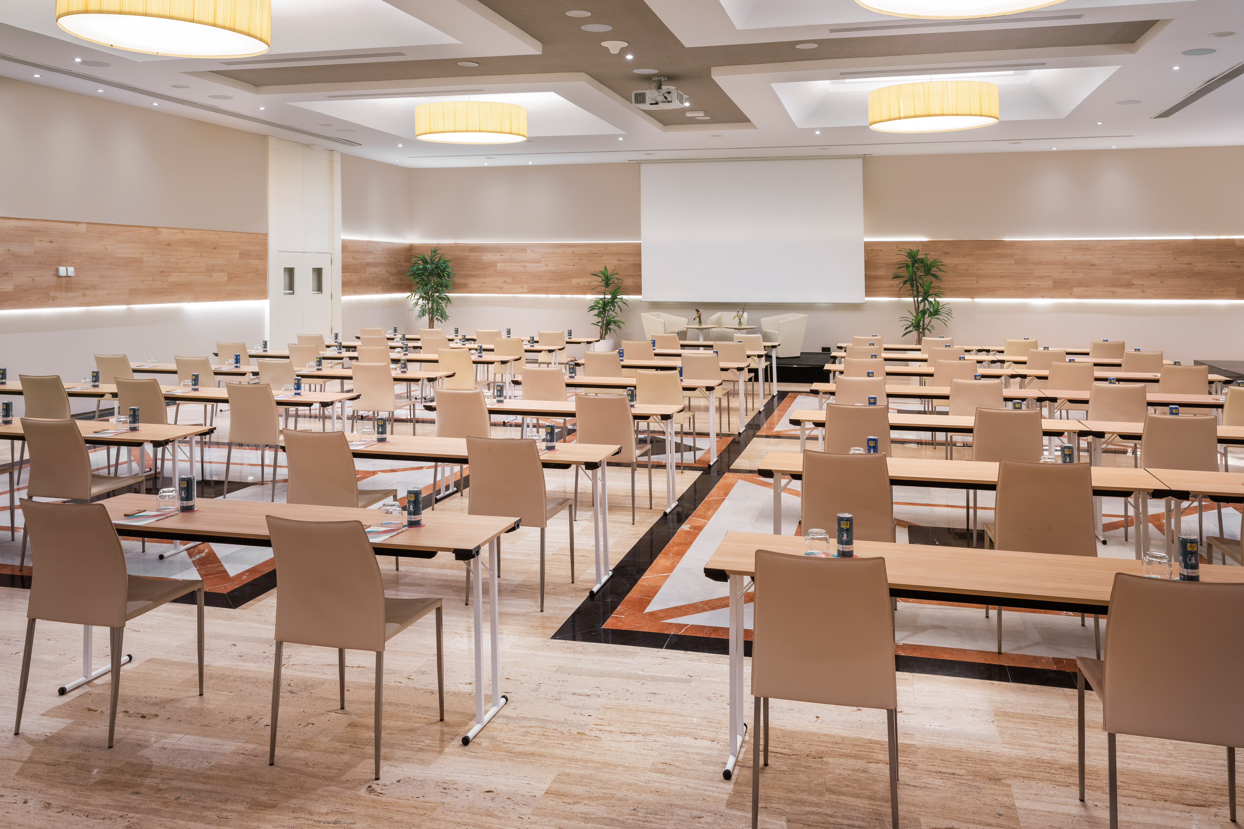 Modern meeting room with tables, chairs, and a presentation screen.