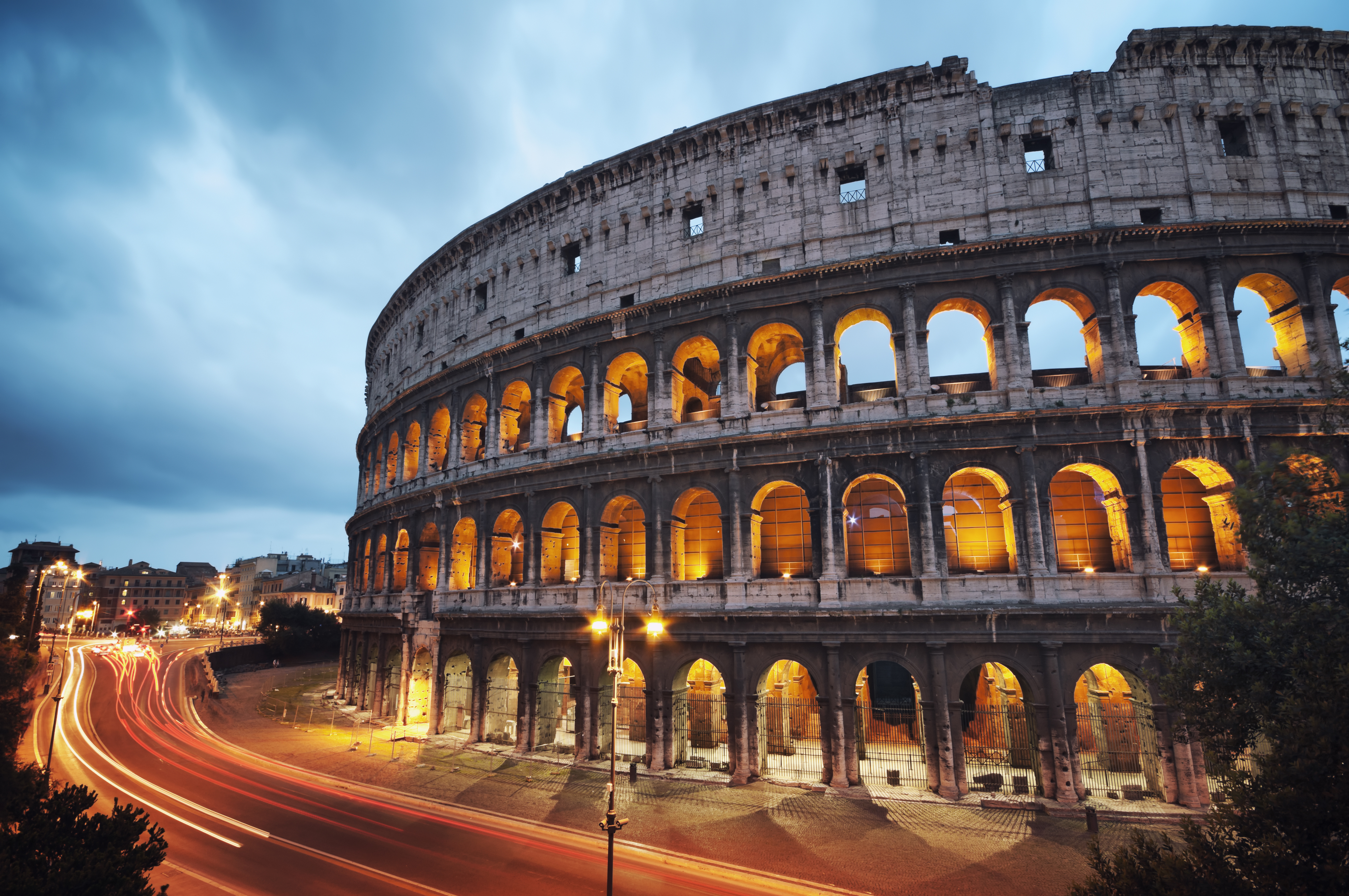 a large stone building with arches with Colosseum in the background