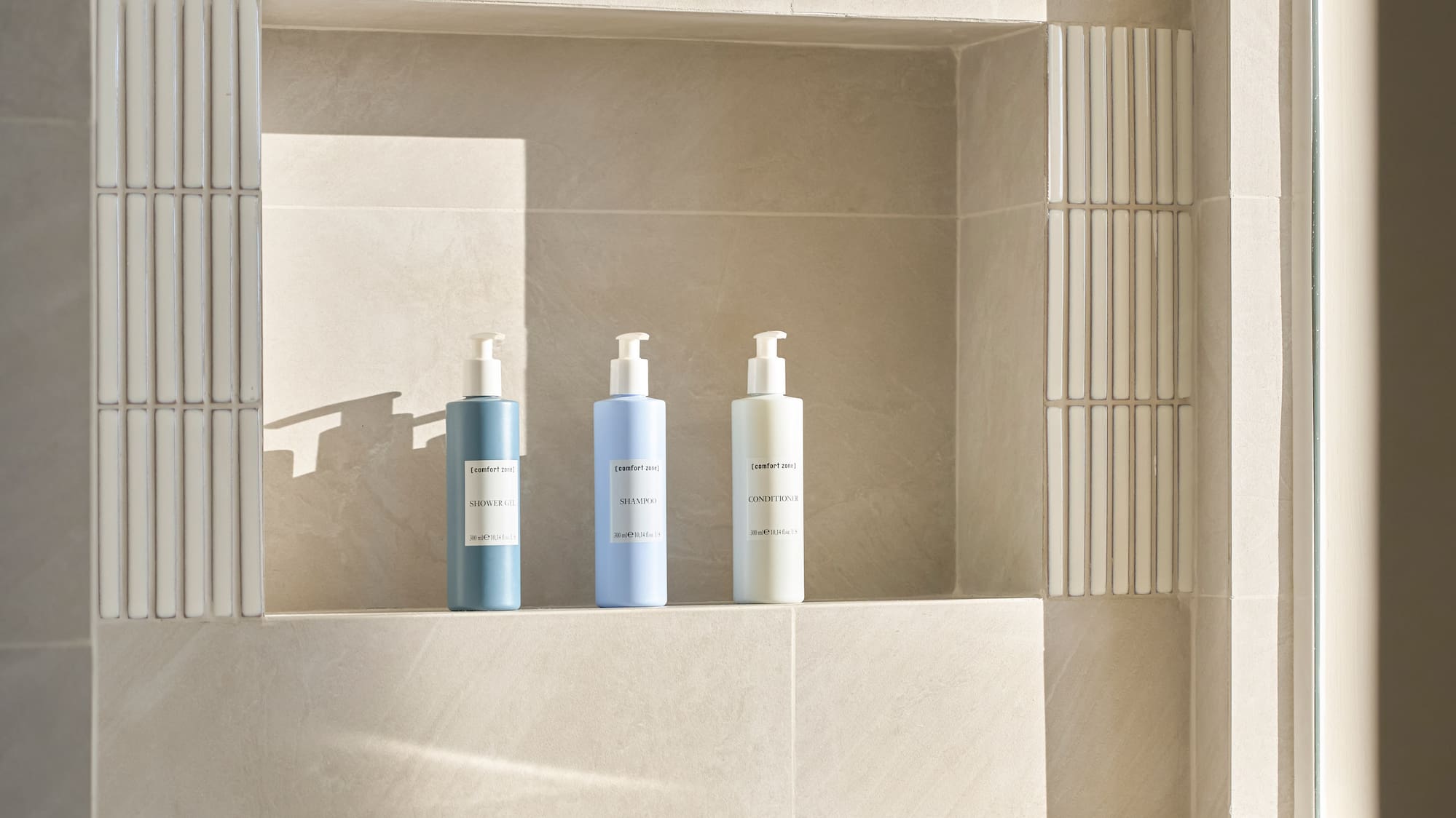 Tiled bathroom niche with minimalist toiletries above a modern bathtub with caddy.