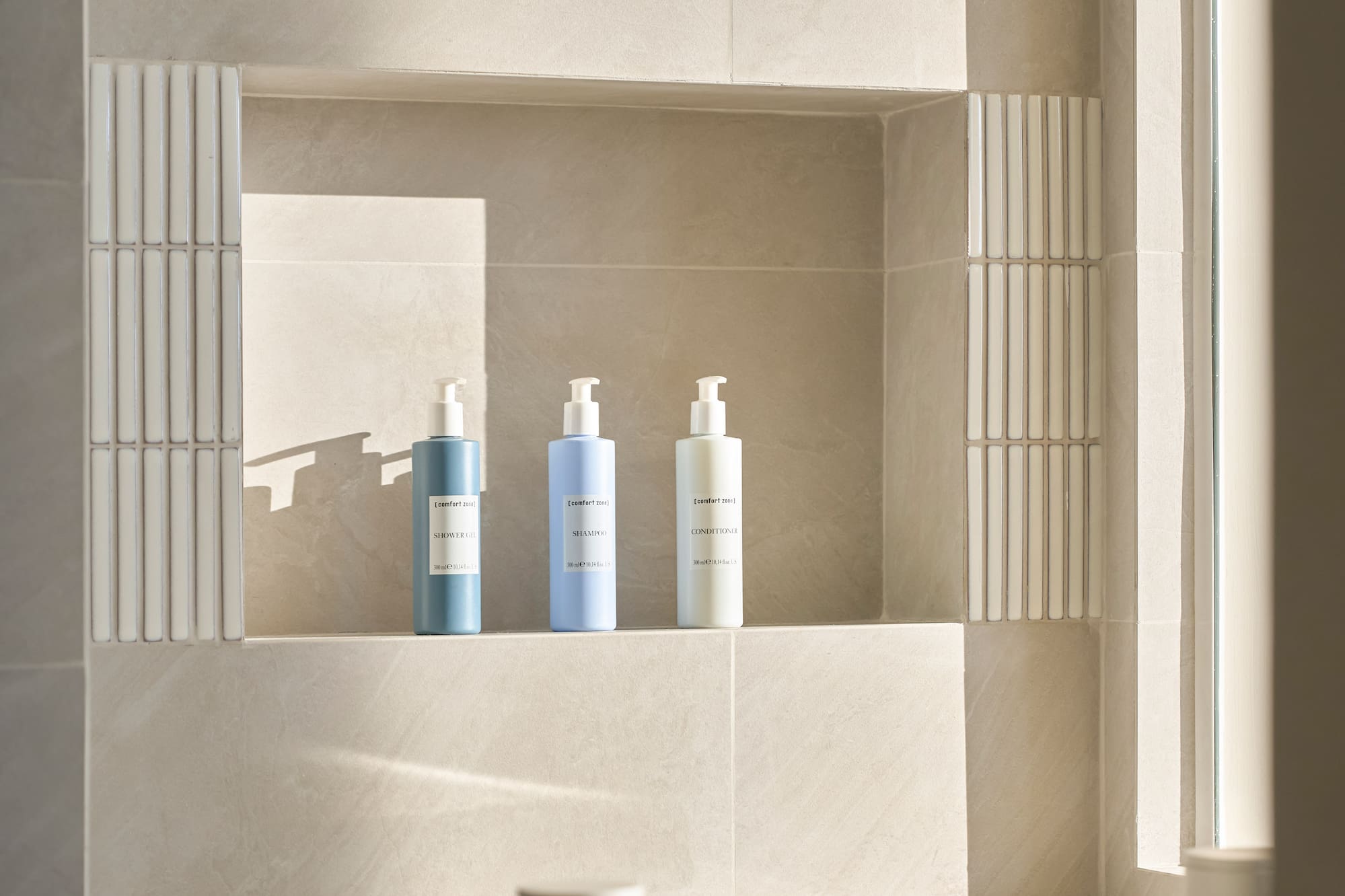 Tiled bathroom niche with minimalist toiletries above a modern bathtub with caddy.