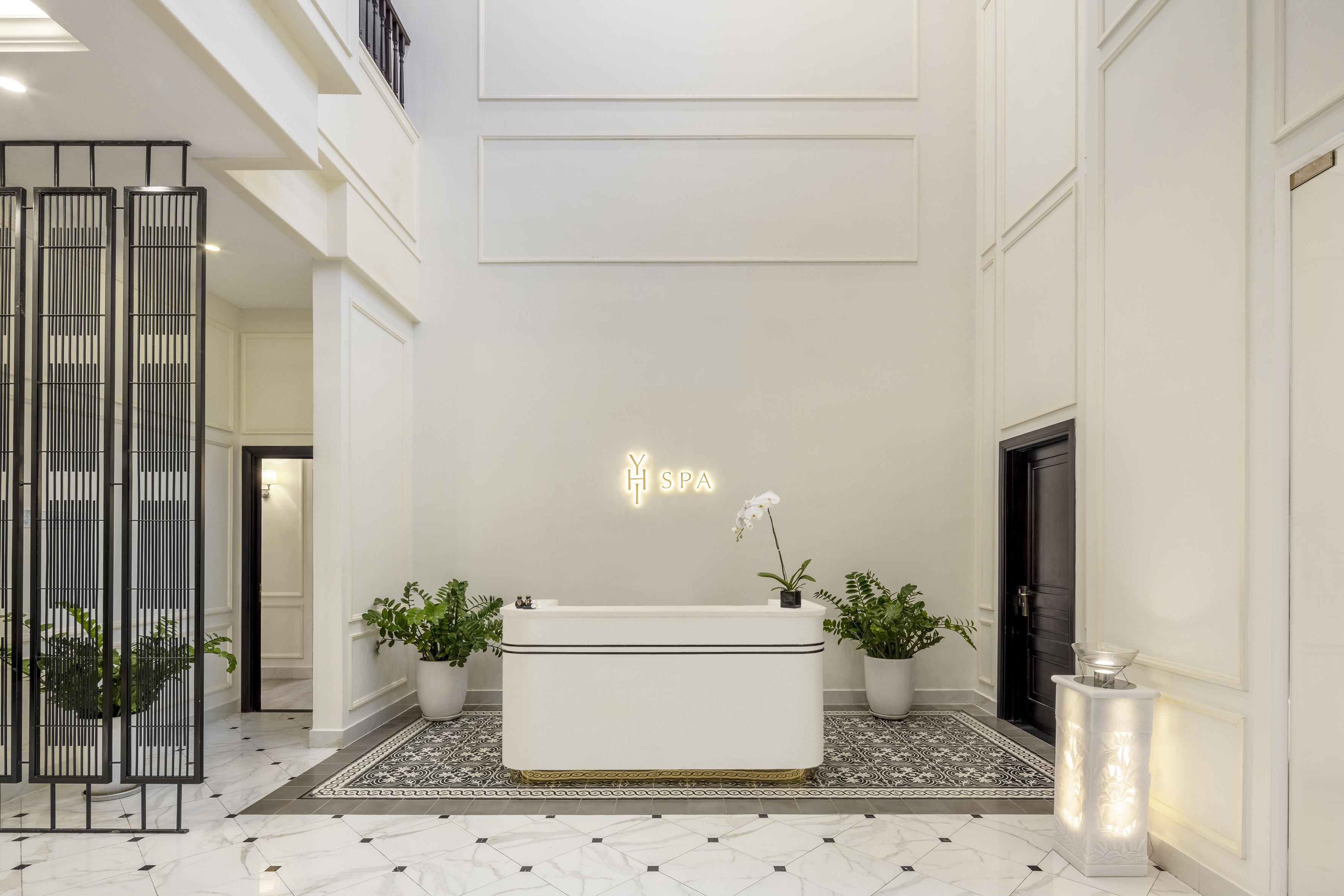 Modern Y SPA lobby with white reception desk, neon sign, and potted plants.