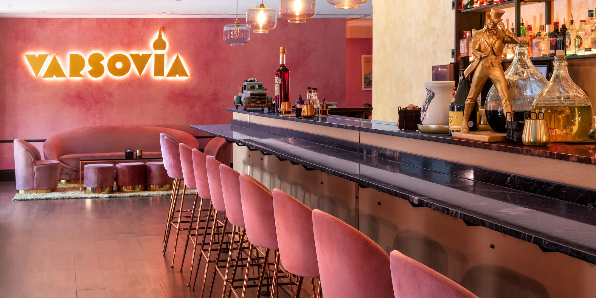 a bar with pink chairs and a sign