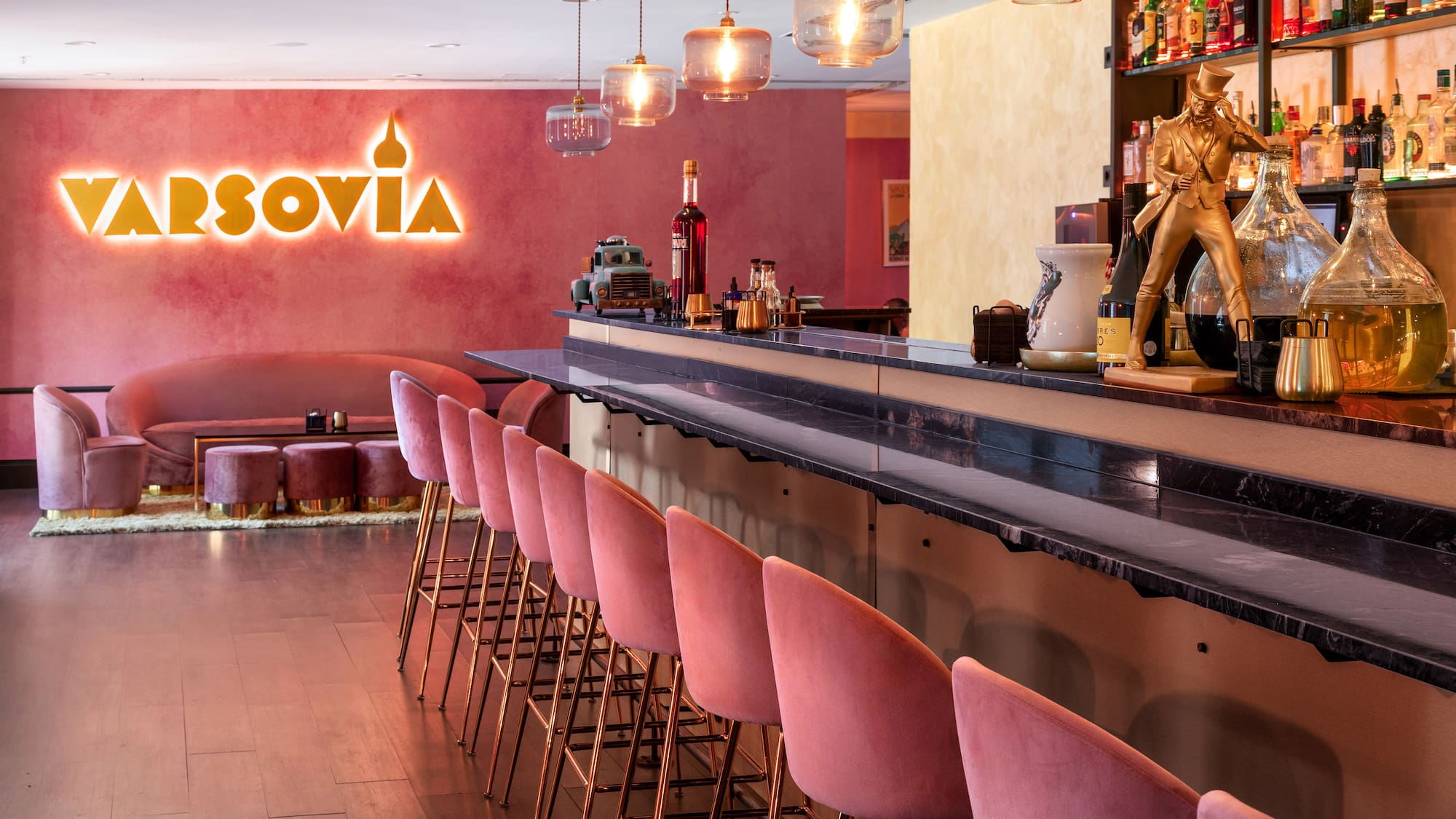 a bar with pink chairs and a sign