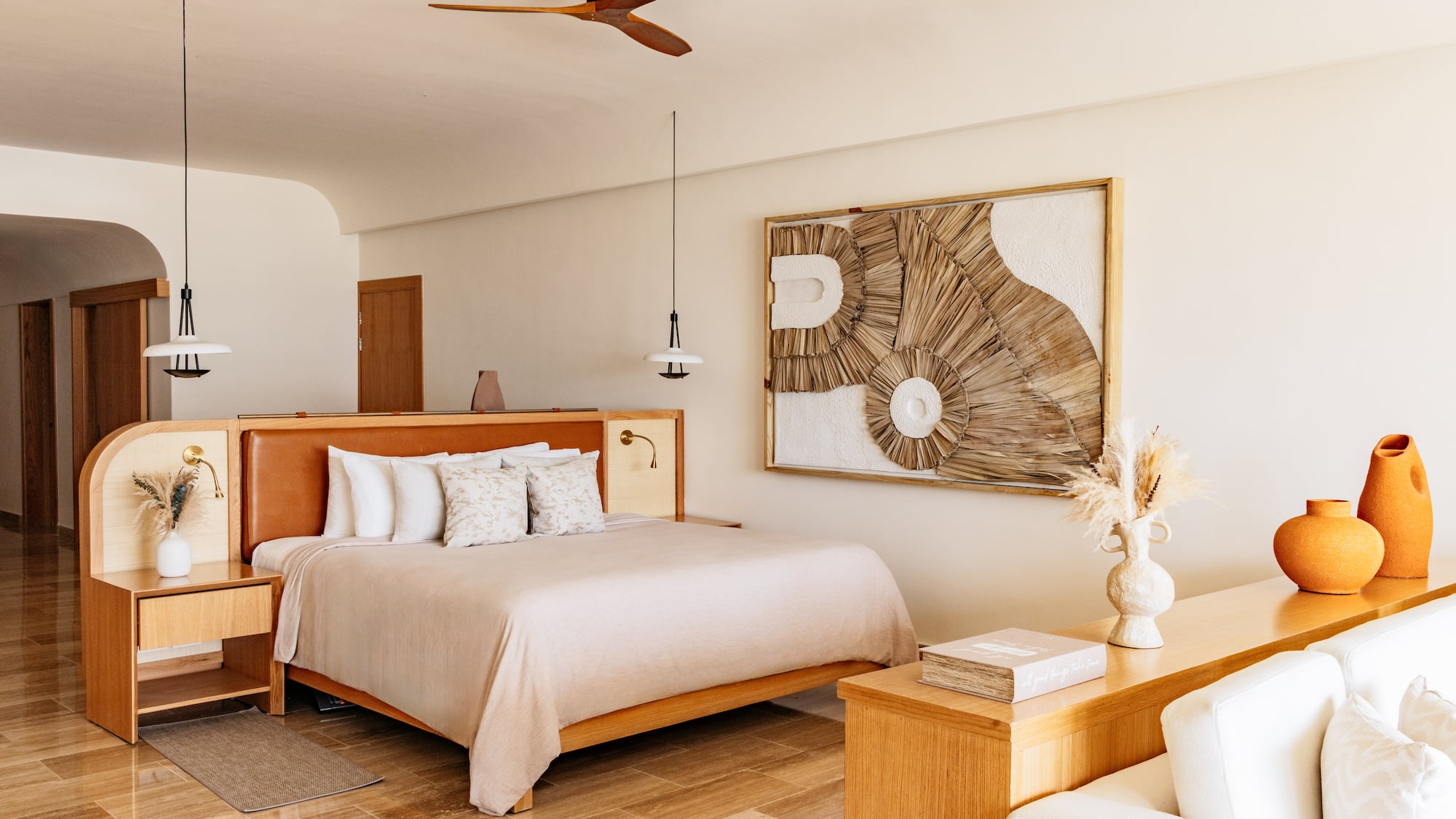 Stylish hotel bedroom with king bed, woven art, neutral tones, and minimalist decor.
