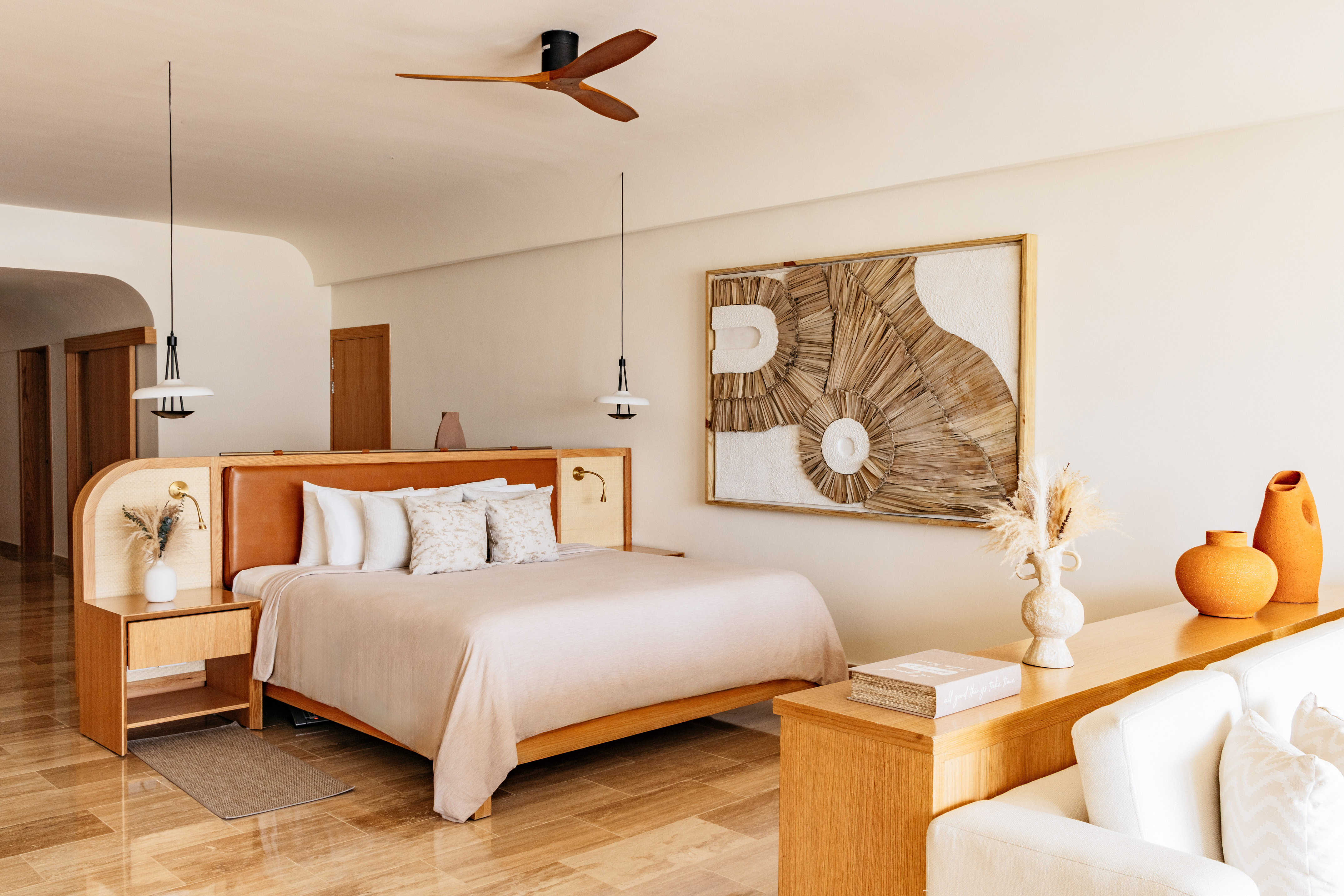 Stylish hotel bedroom with king bed, woven art, neutral tones, and minimalist decor.