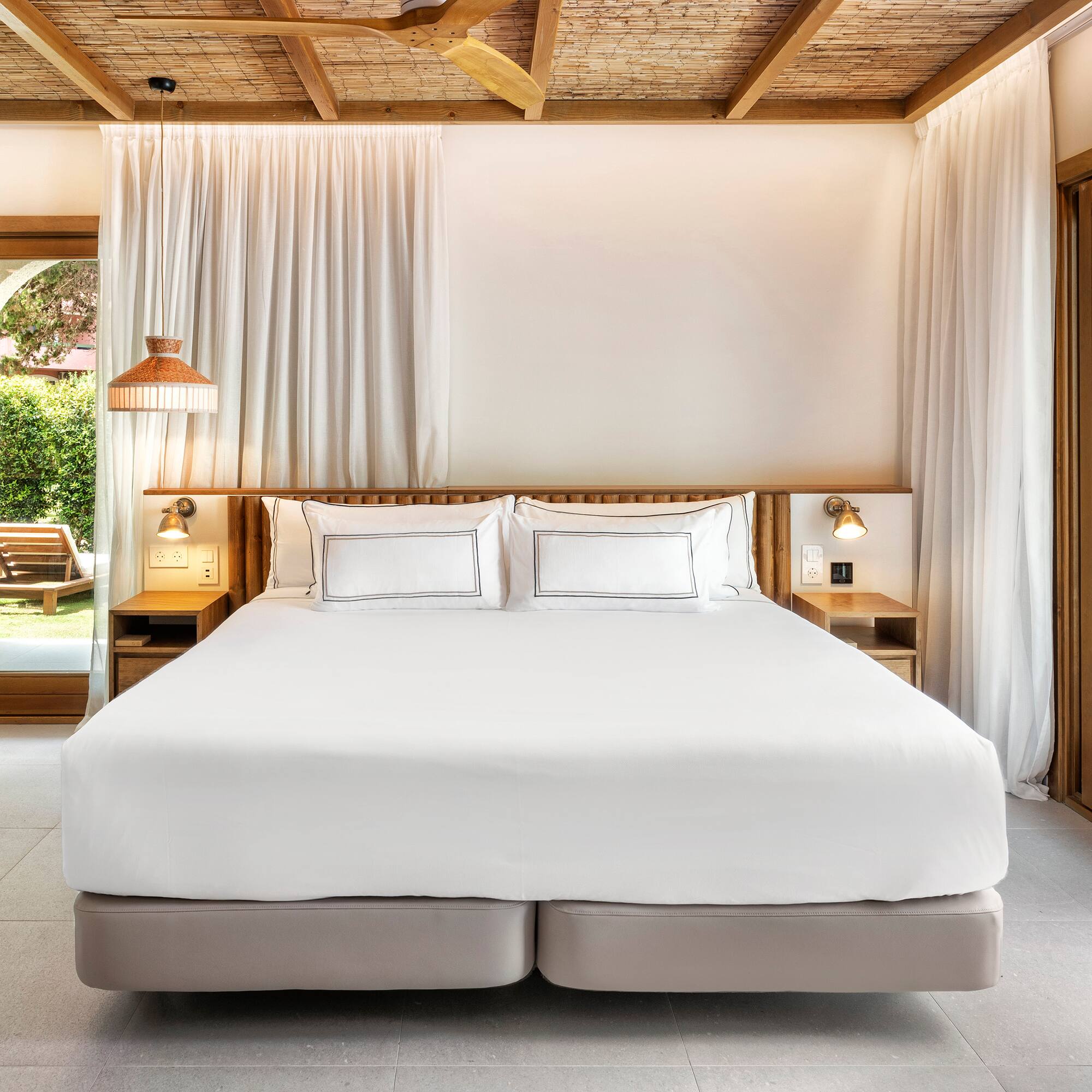 a bed with white sheets and lamps in a room with a wood ceiling