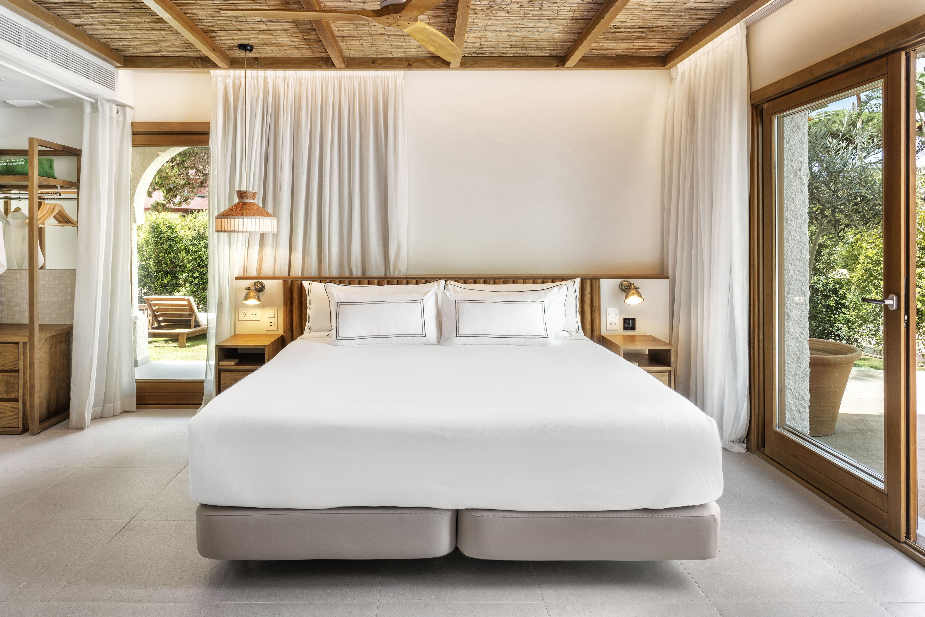 a bed with white sheets and lamps in a room with a wood ceiling