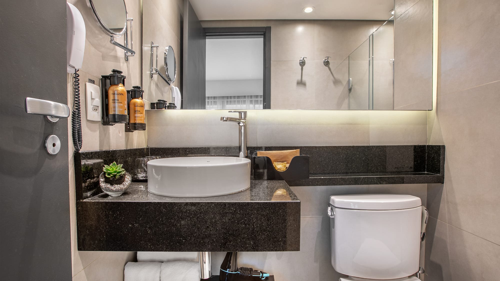 Modern hotel bathroom with white vessel sink, black granite countertop, and toilet. - Deluxe Queen Room com Varanda - Meliá Ibirapuera, São Paulo
