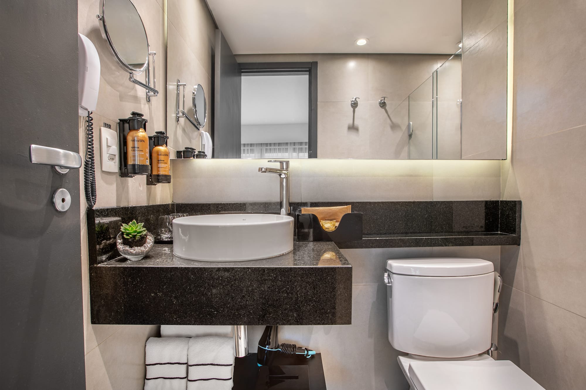 Modern hotel bathroom with white vessel sink, black granite countertop, and toilet. - Deluxe Queen Room com Varanda - Meliá Ibirapuera, São Paulo