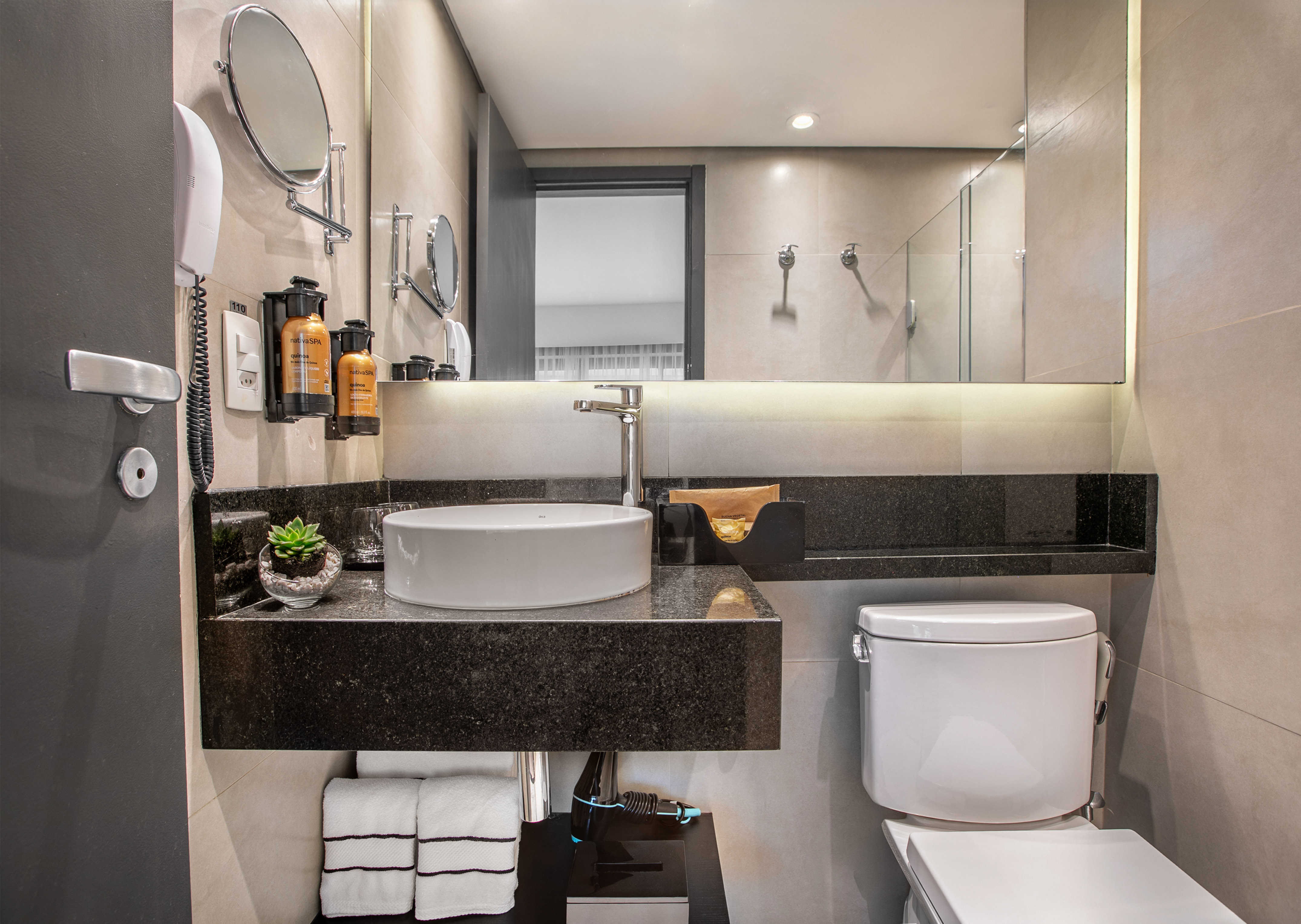 Modern hotel bathroom with white vessel sink, black granite countertop, and toilet. - Deluxe Queen Room com Varanda - Meliá Ibirapuera, São Paulo