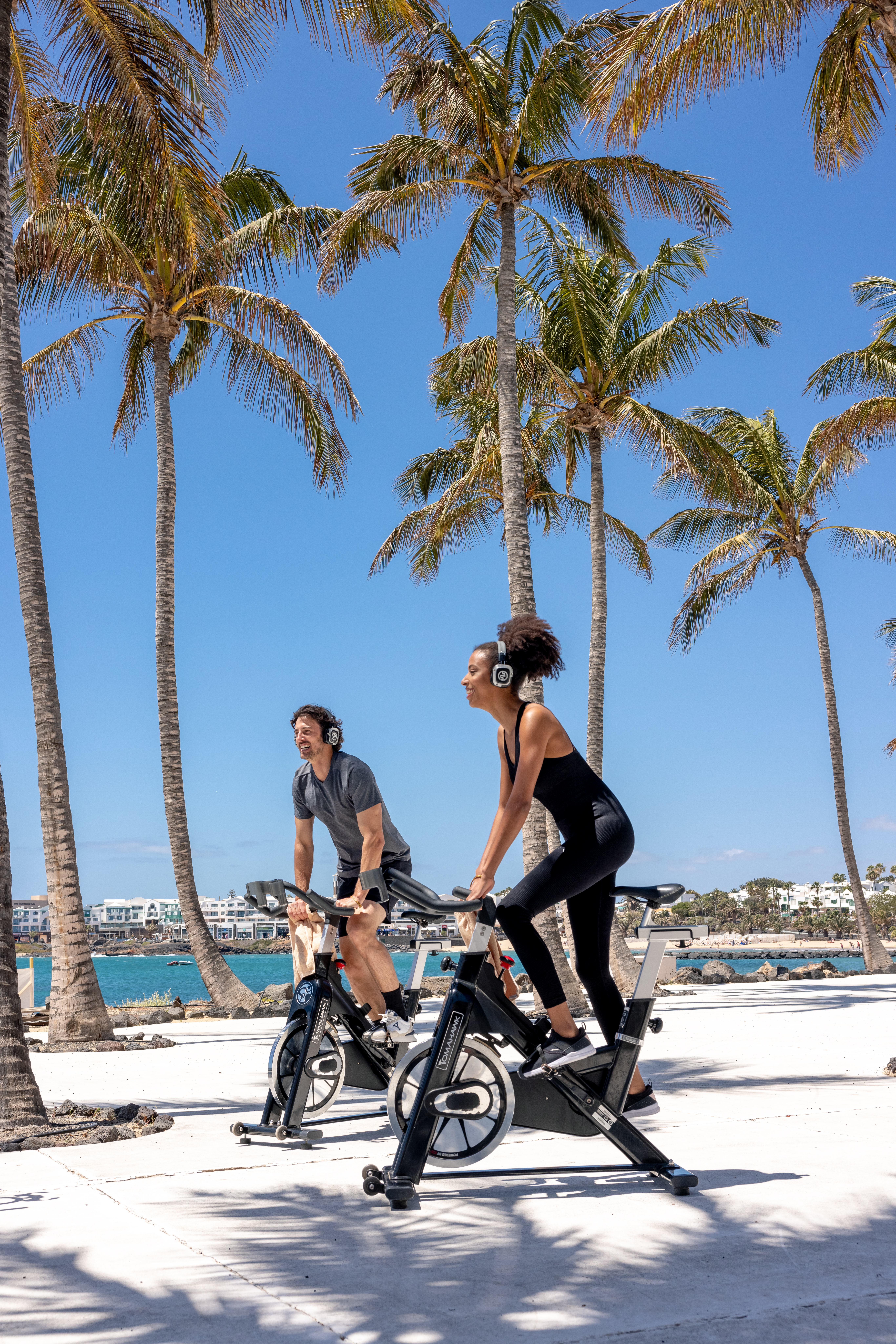 a man and woman riding bicycles on a beach