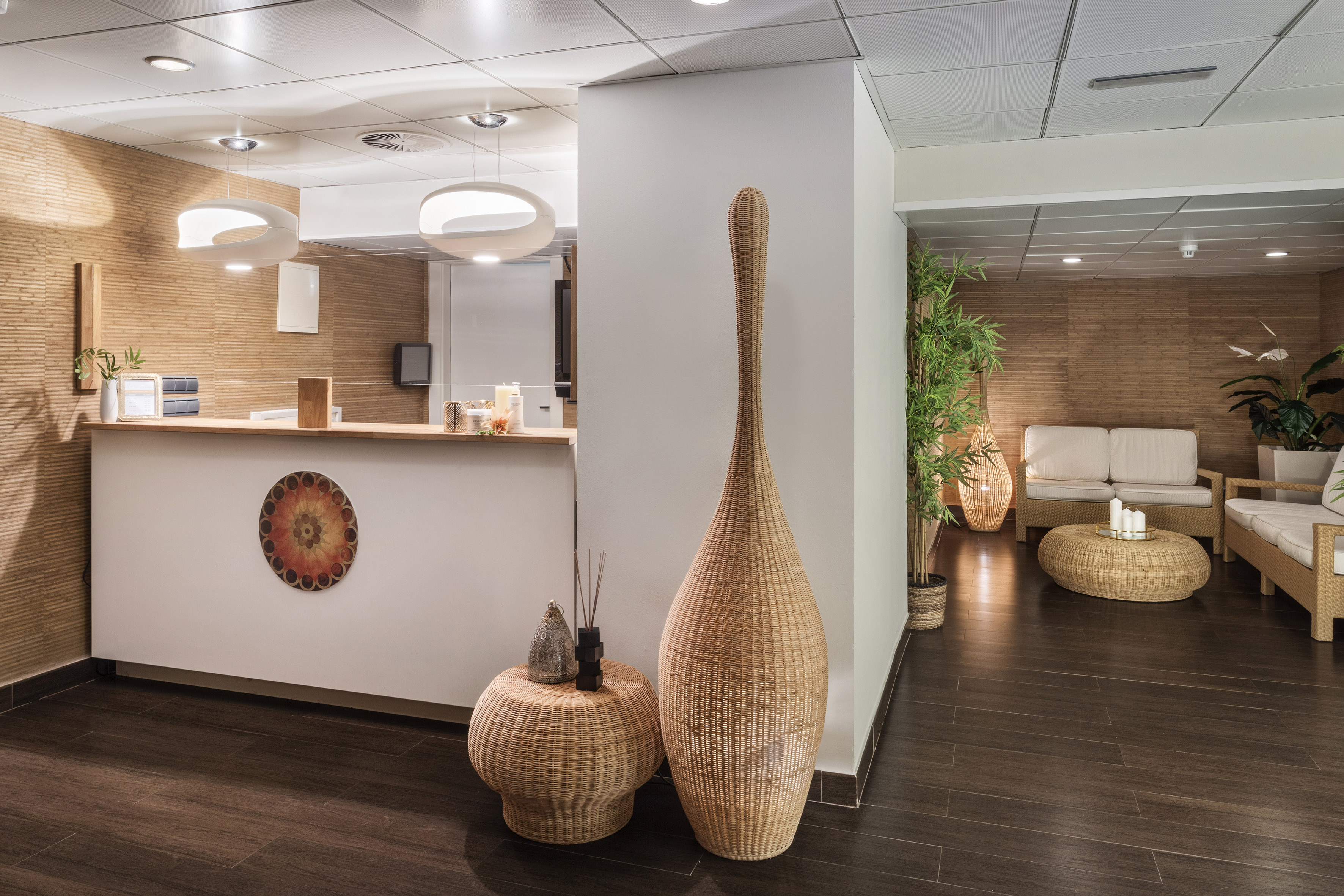 Hotel reception and lobby with natural wood walls and wicker furniture.