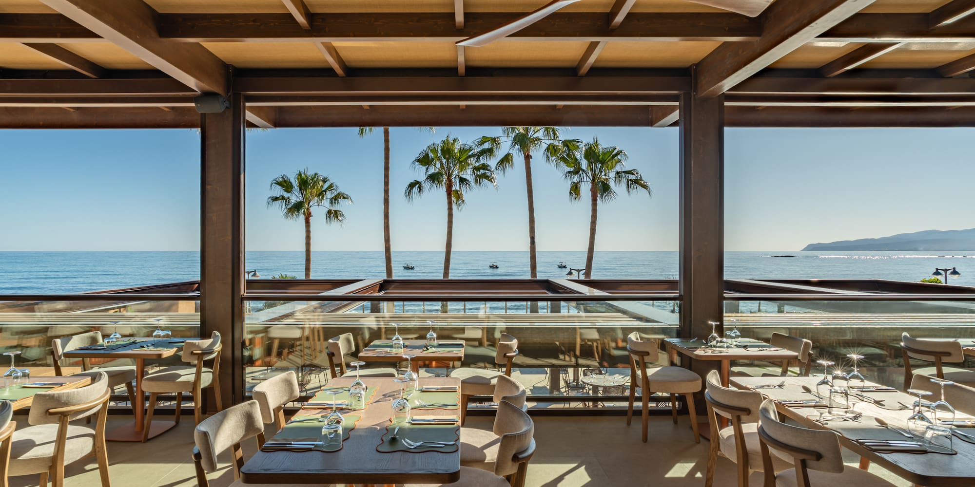 Beachfront restaurant with ocean views, palm trees, and outdoor dining.