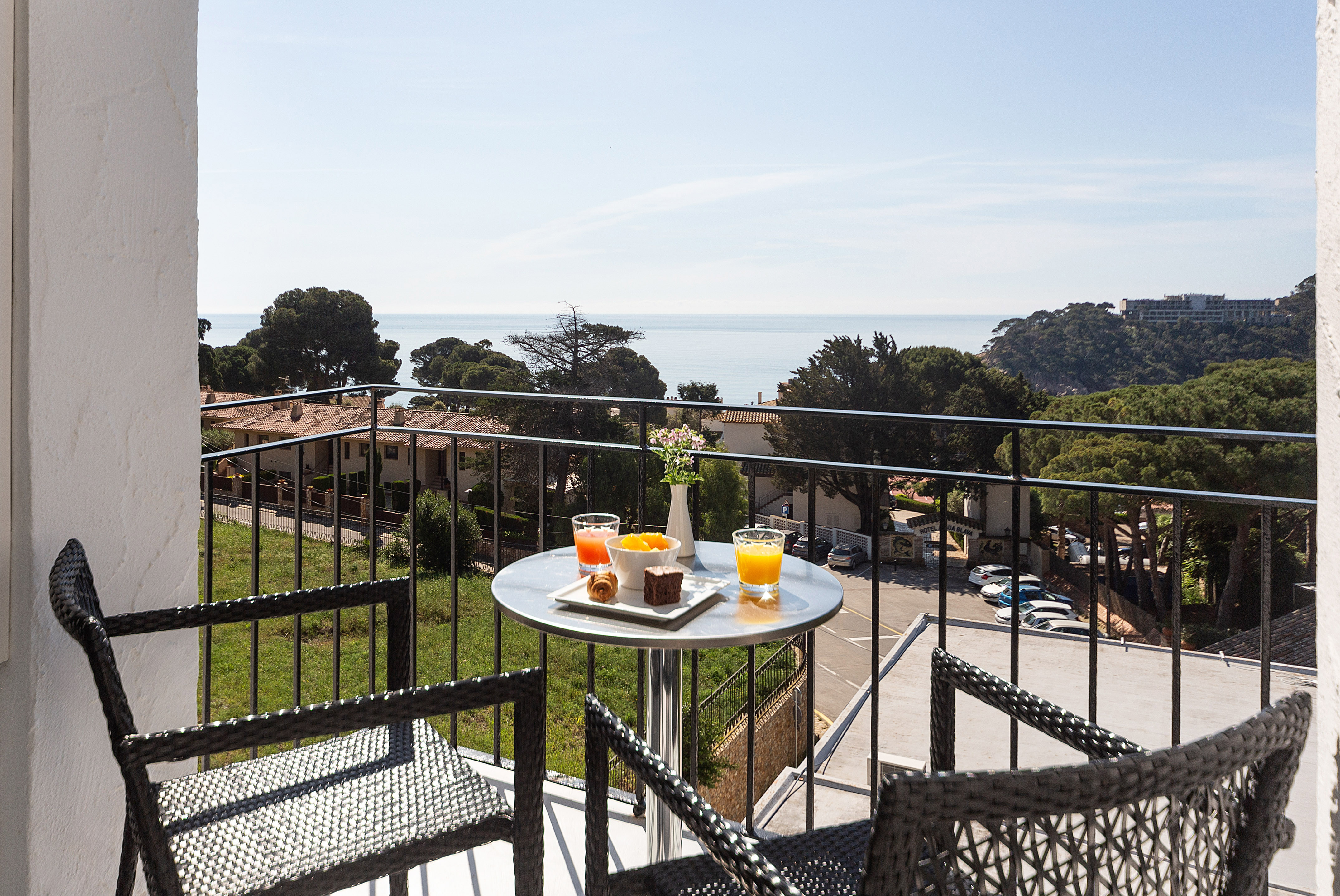 Hotel balcony with breakfast, ocean view, and coastal landscape.