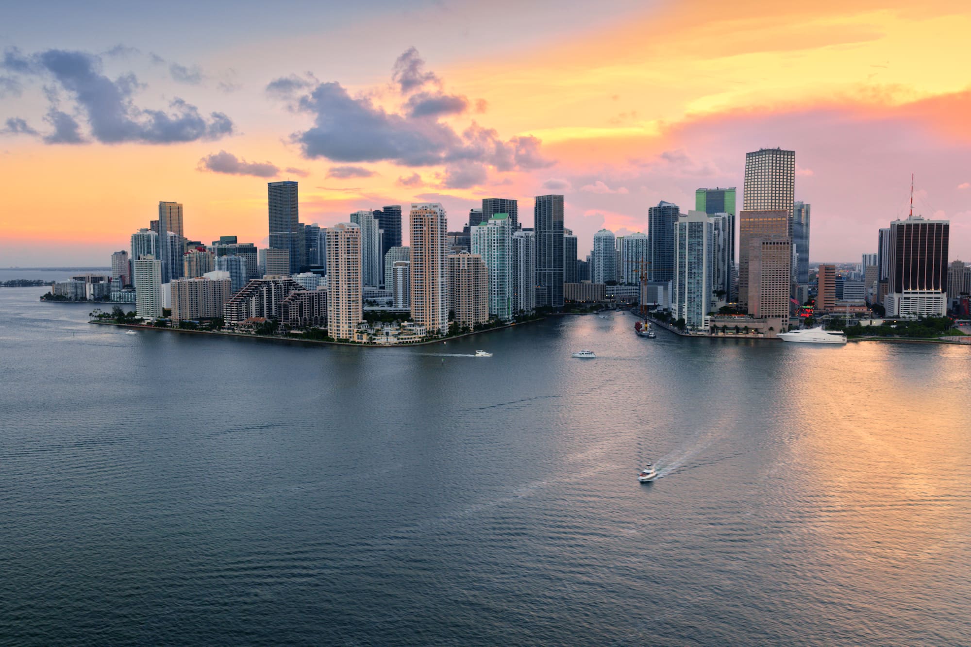 Skyline de Miami al atardecer sobre la bahía, con rascacielos y barcos.