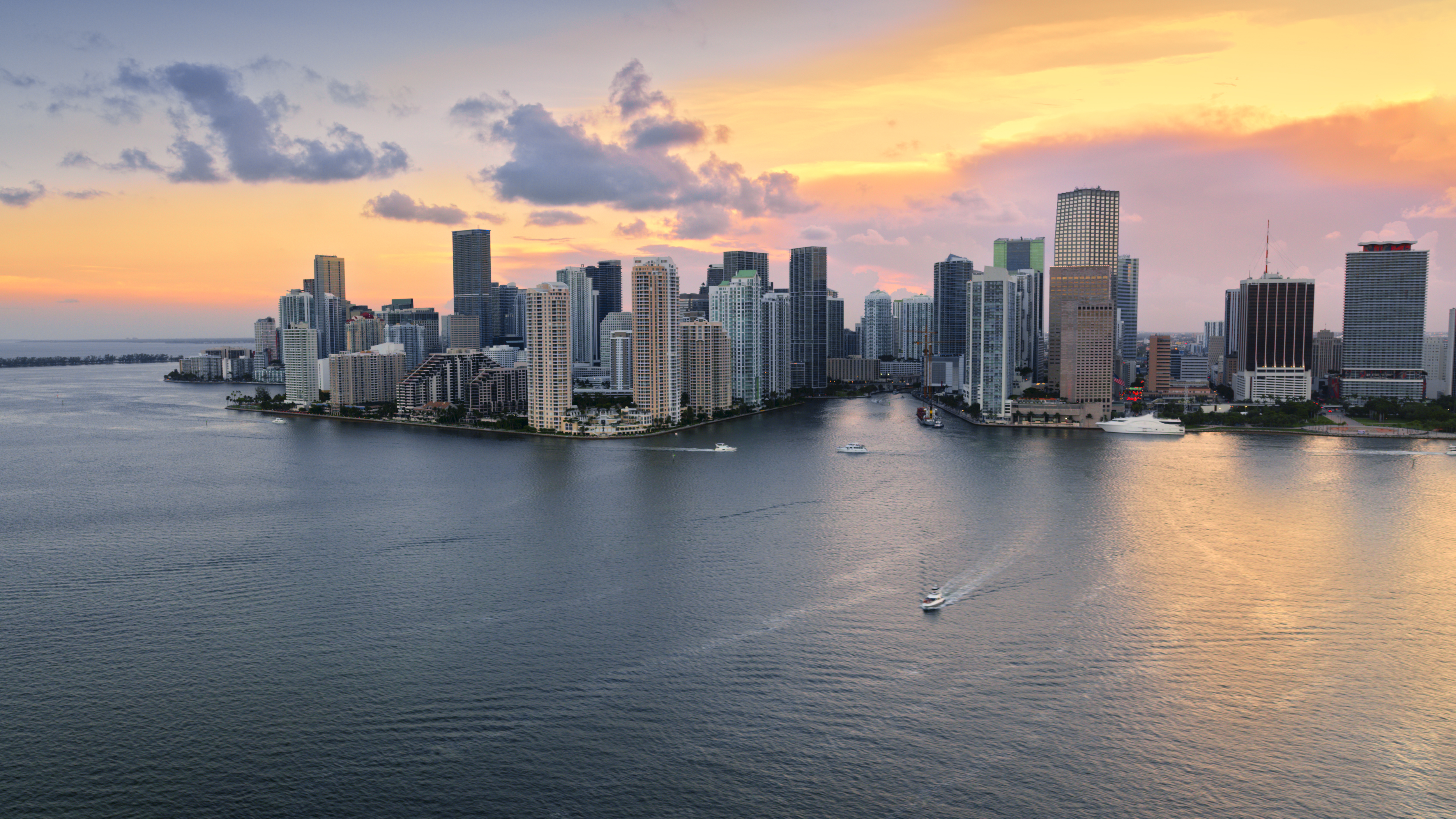 Skyline de Miami al atardecer sobre la bahía, con rascacielos y barcos.
