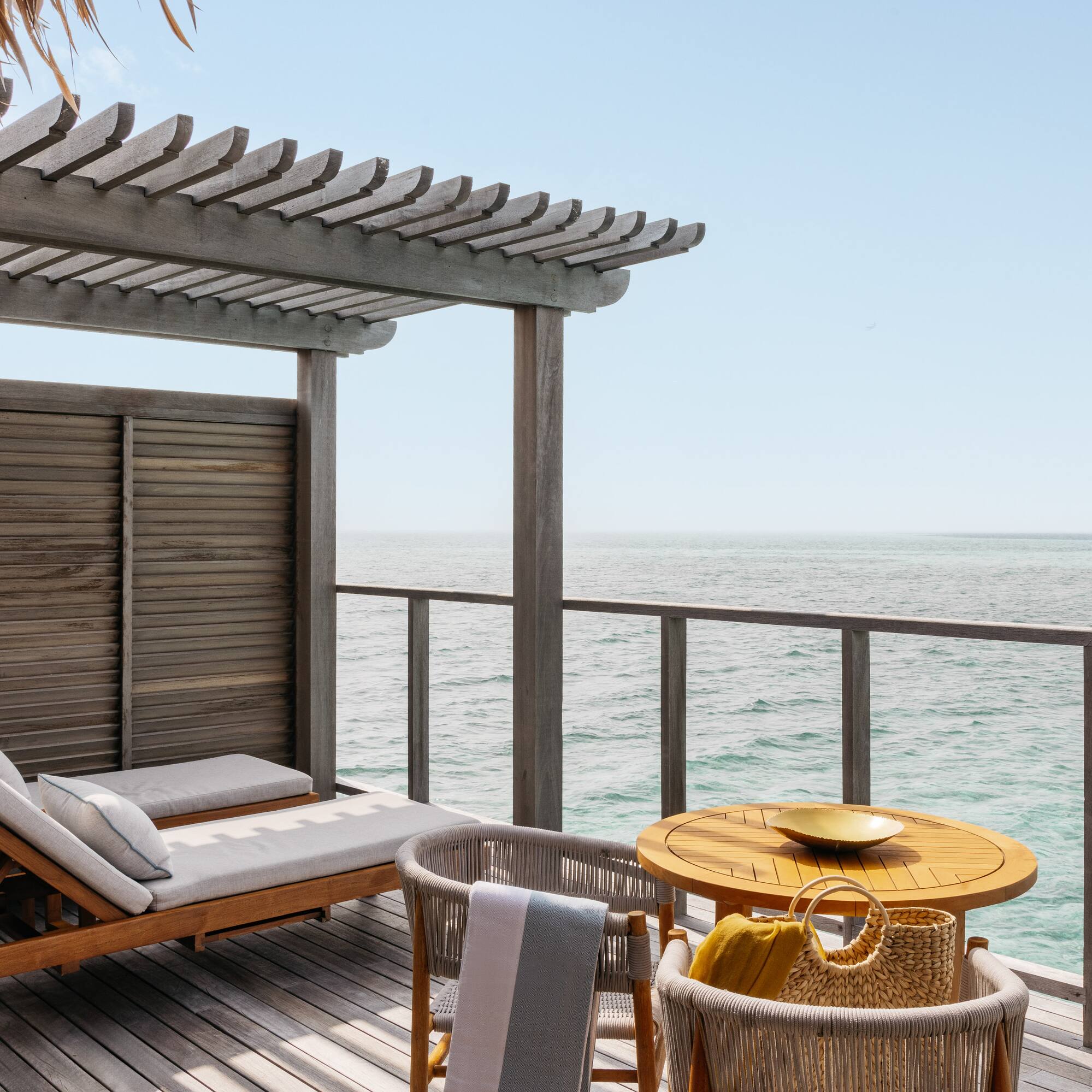 a deck with a table and chairs overlooking the ocean