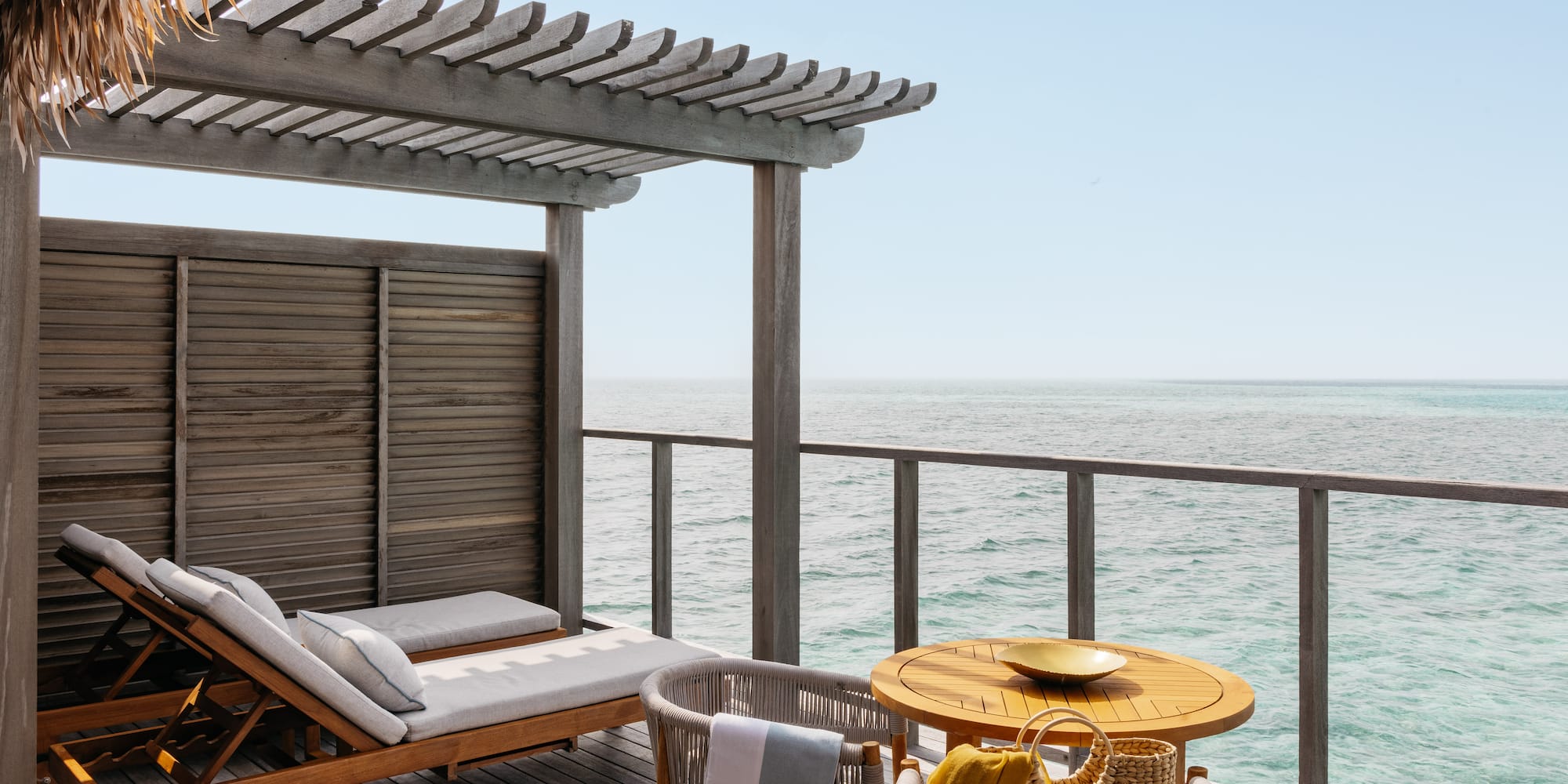 a deck with a table and chairs overlooking the ocean