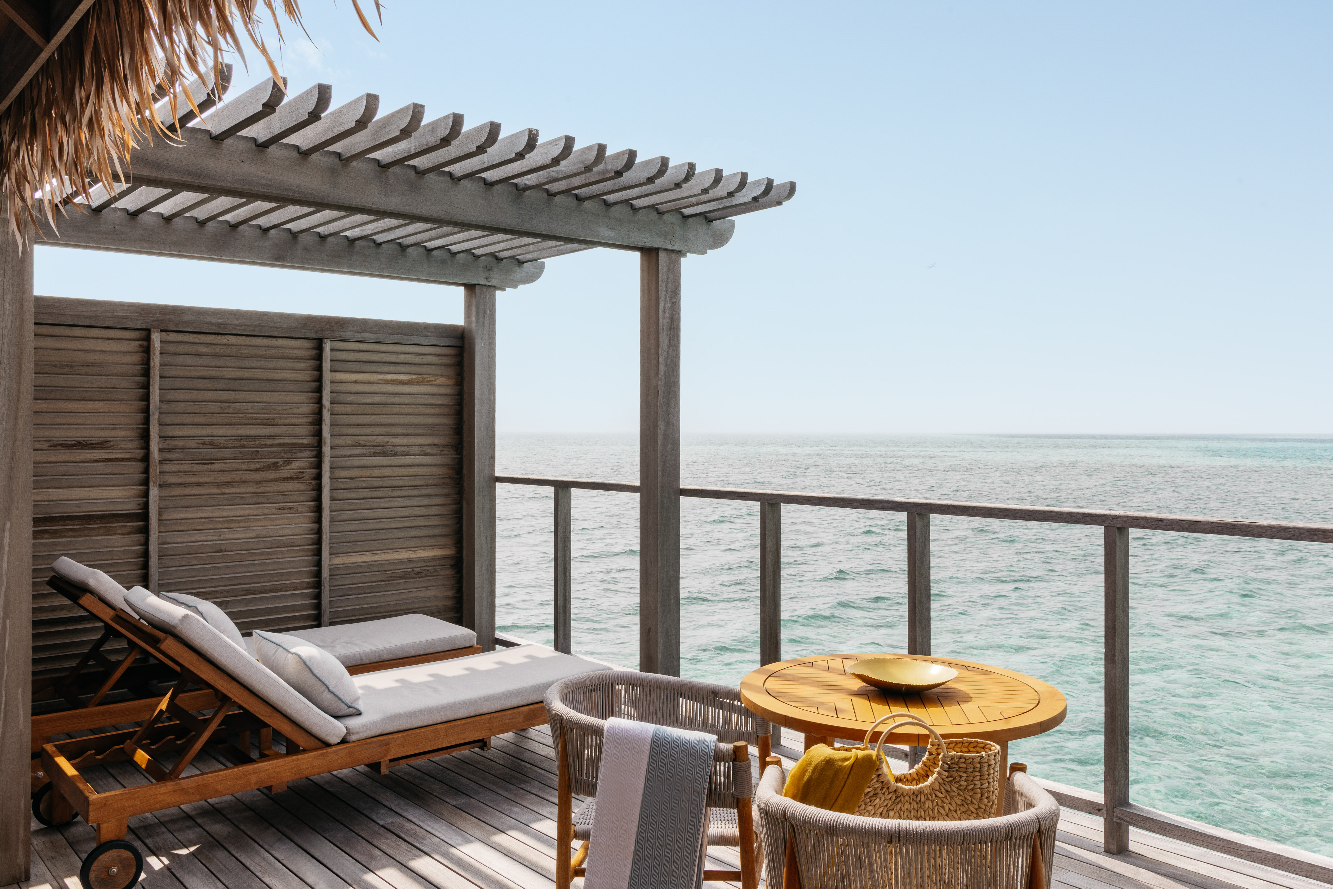 a deck with a table and chairs overlooking the ocean