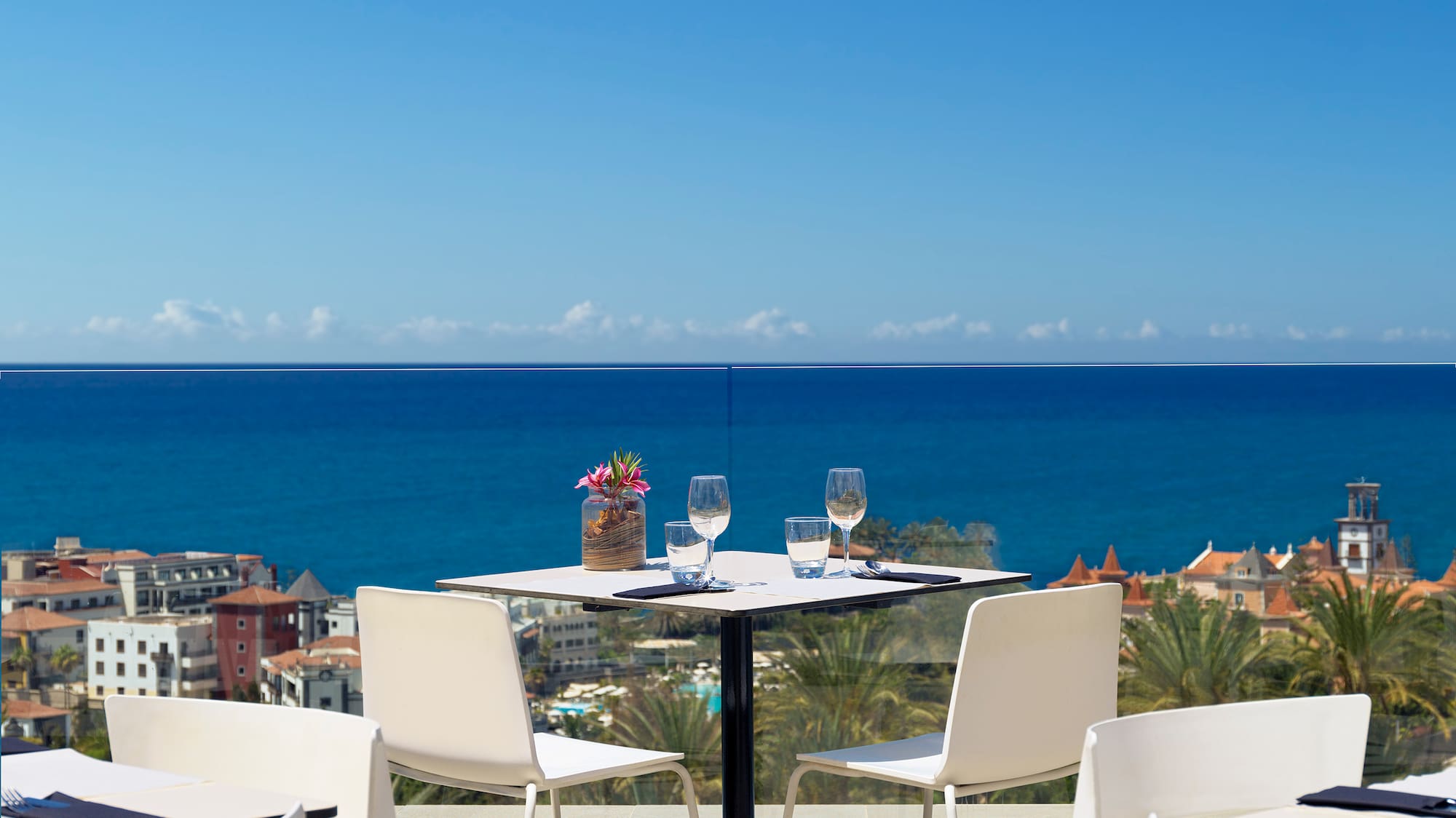 a table and chairs with a view of the ocean