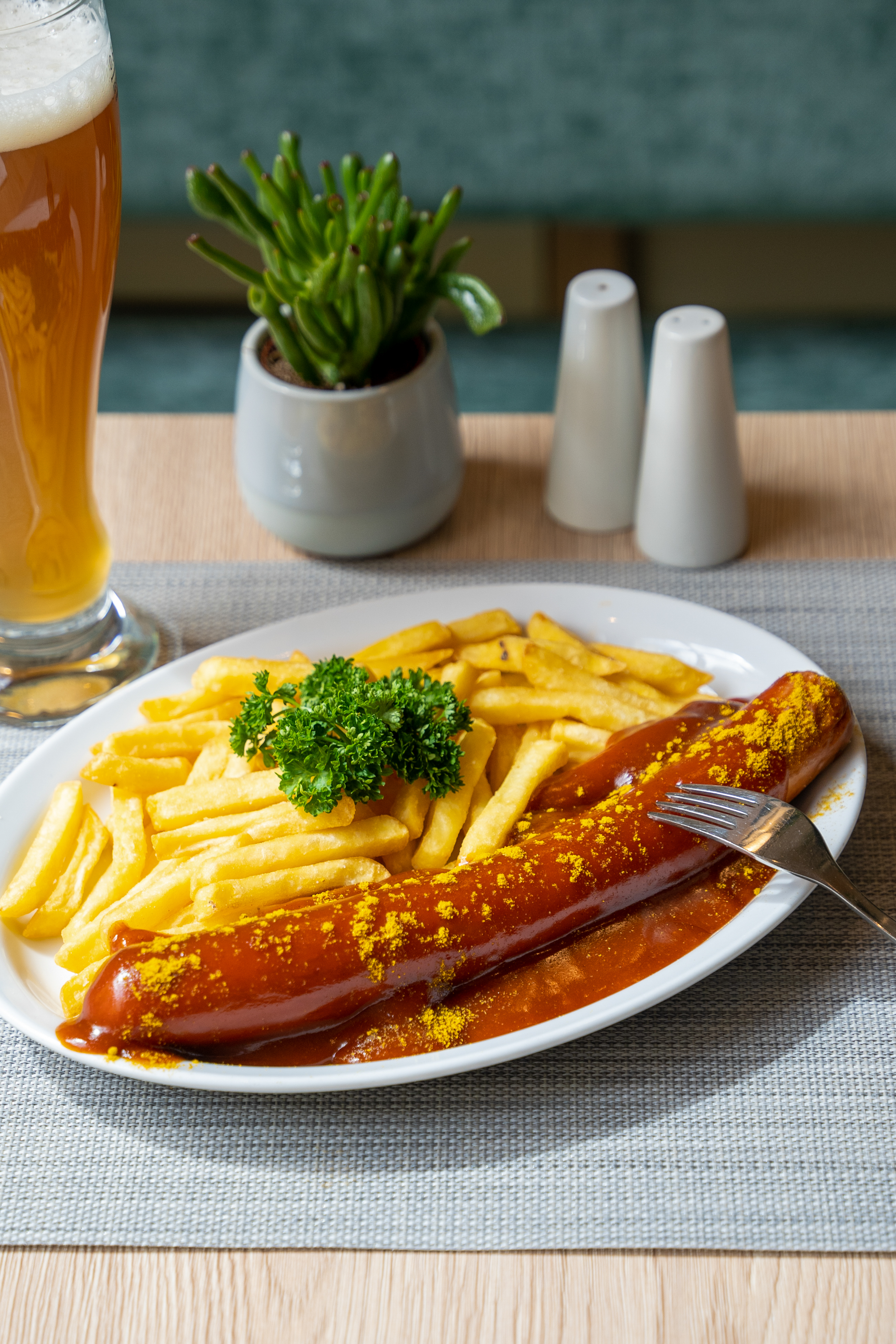 German Currywurst and golden fries with curry powder, sauce, and beer.