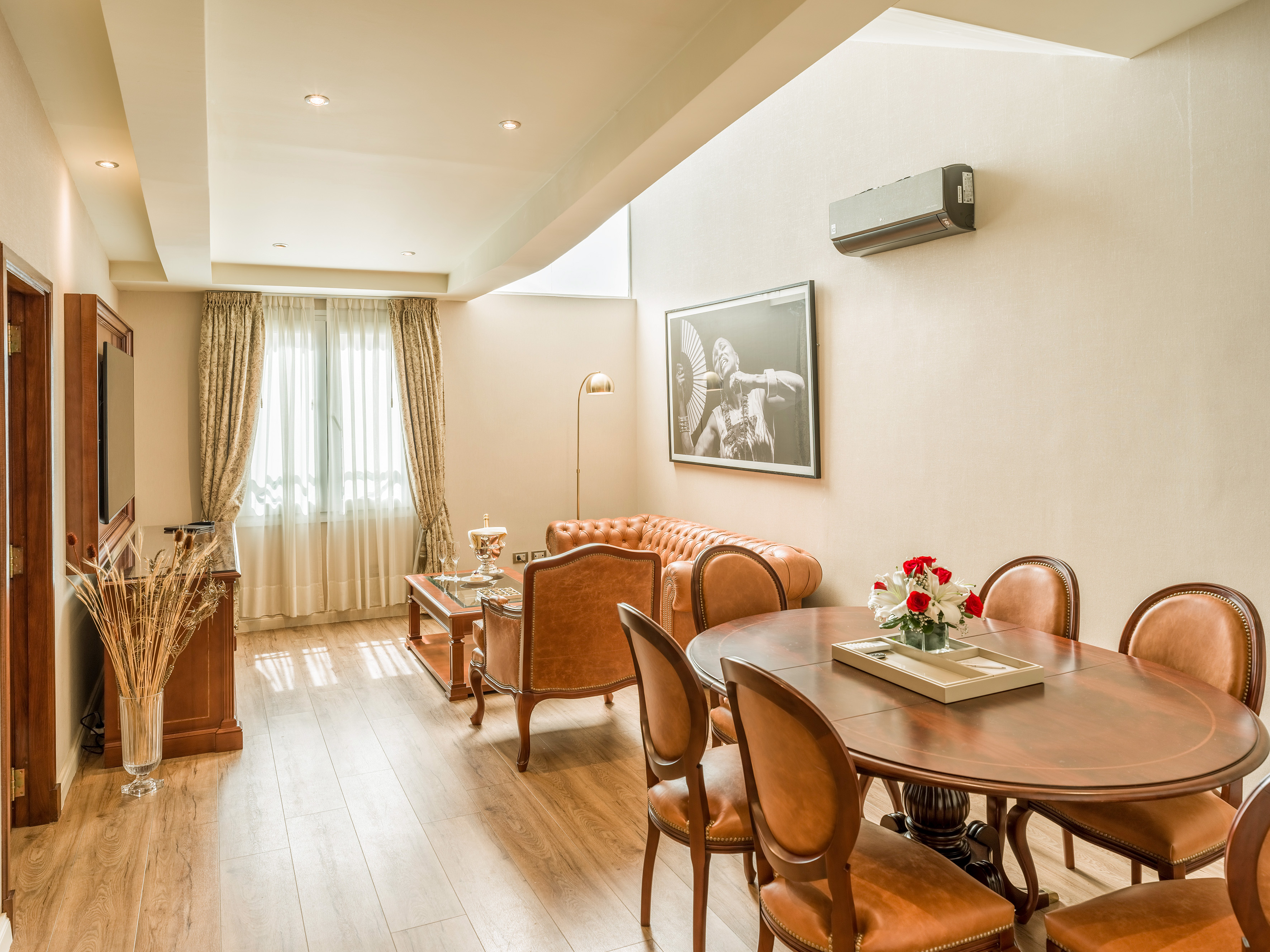 Elegant living-dining room with leather sofa, wooden table, hardwood floor.