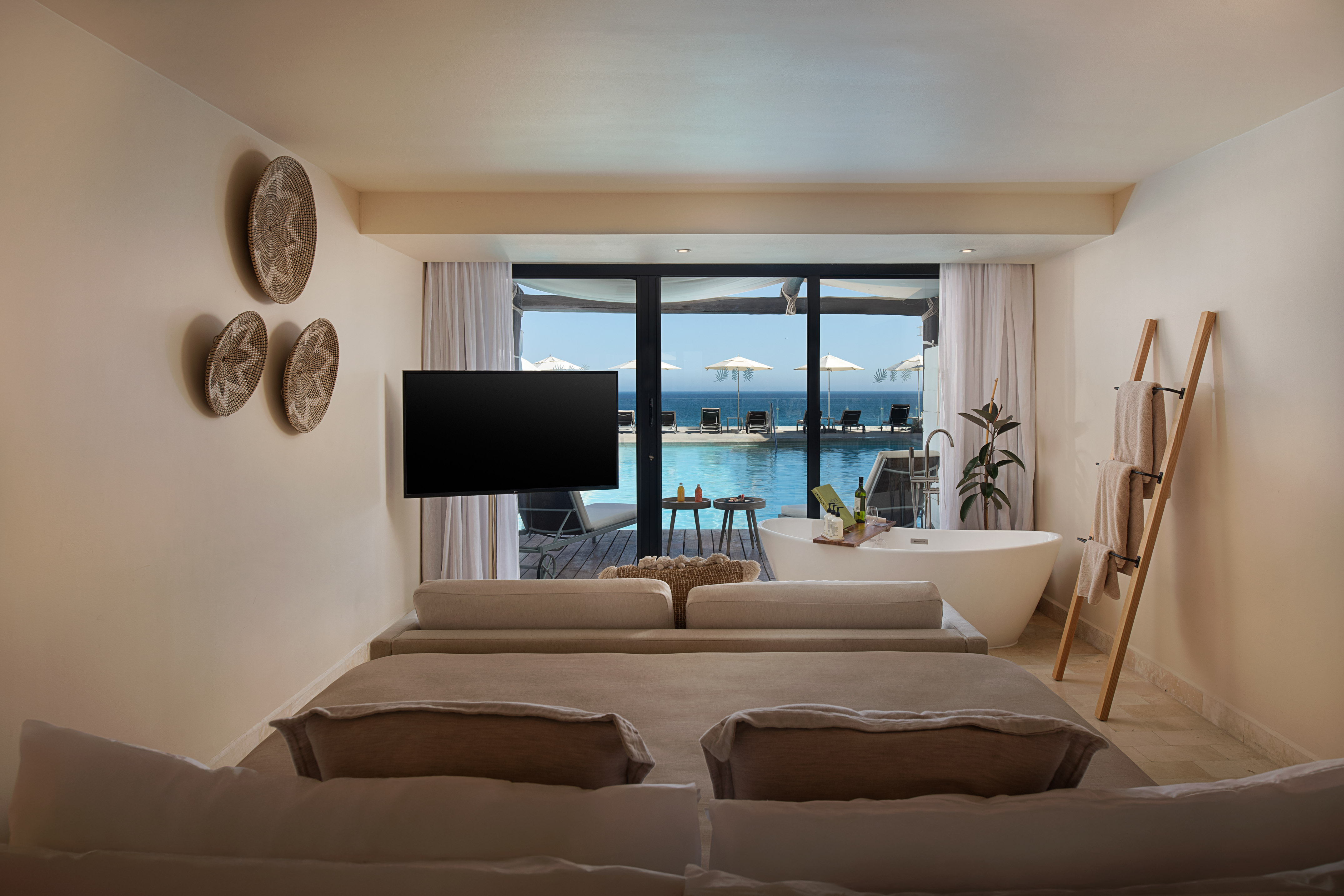 Luxury resort room with ocean view, private pool access, and modern bathtub.