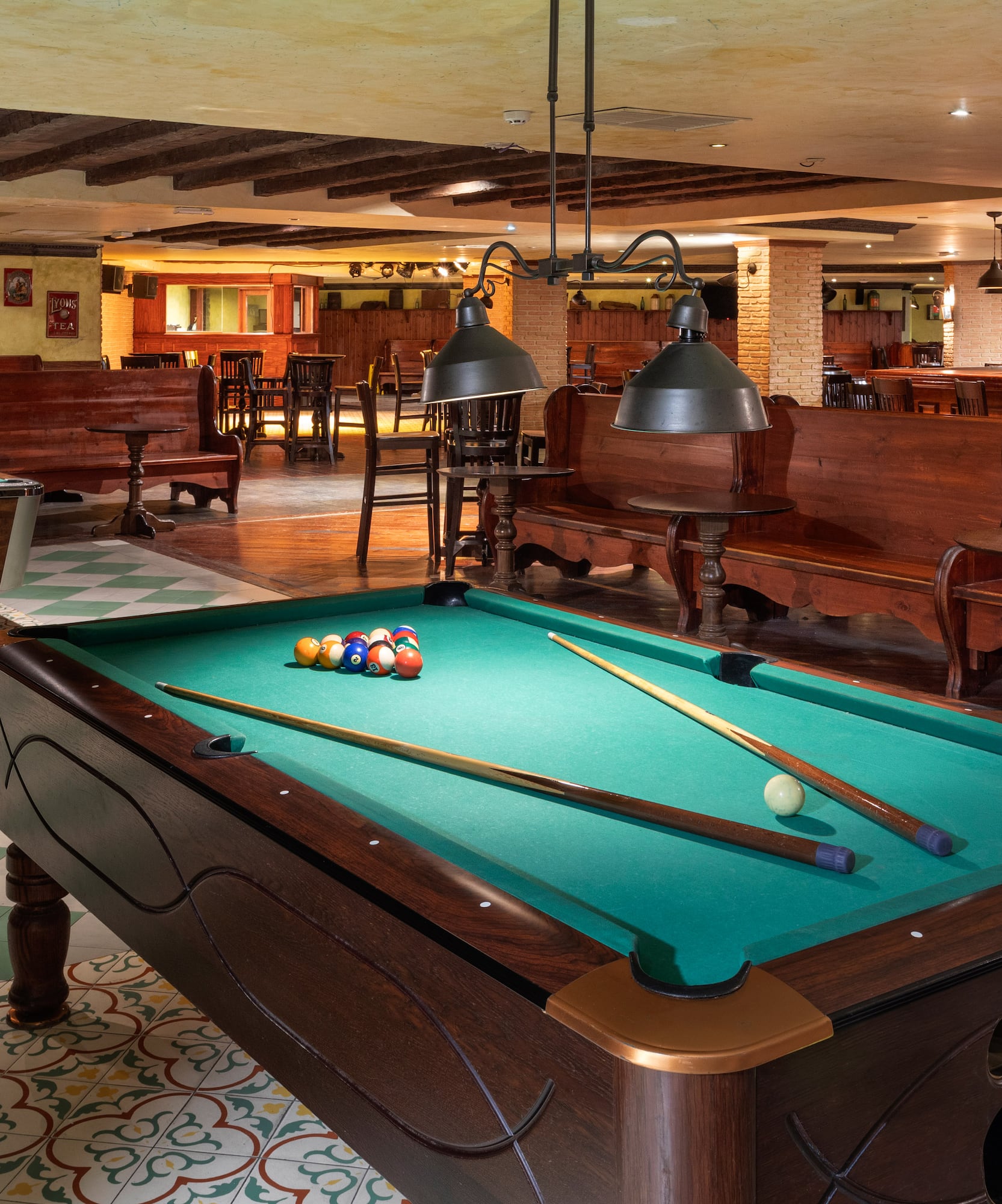 Classic pool hall with two billiard tables, wooden furniture, and warm lighting.