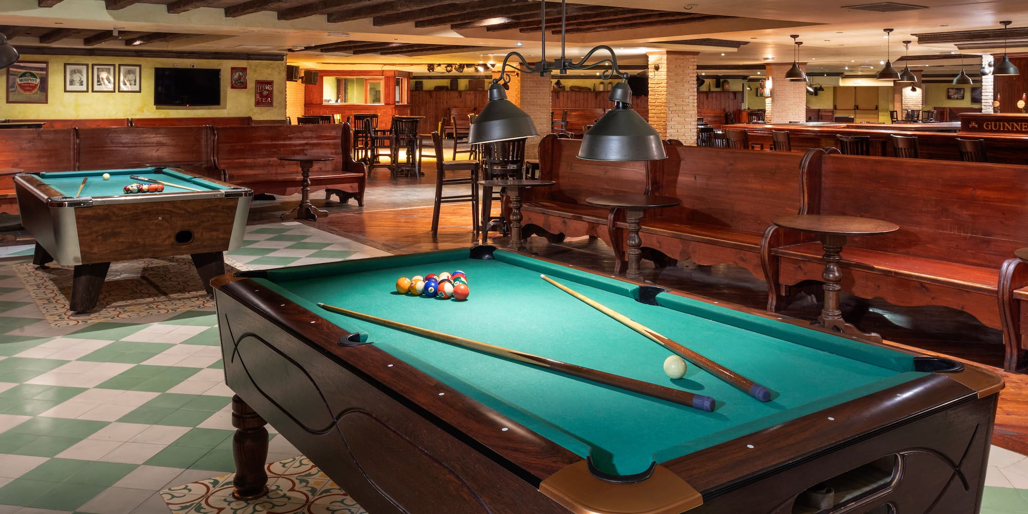 Traditional bar game room featuring two pool tables and classic wood interiors.