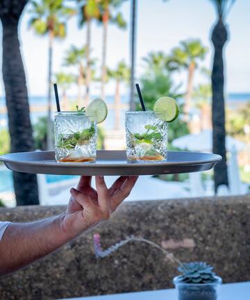 a person holding a tray with drinks on it