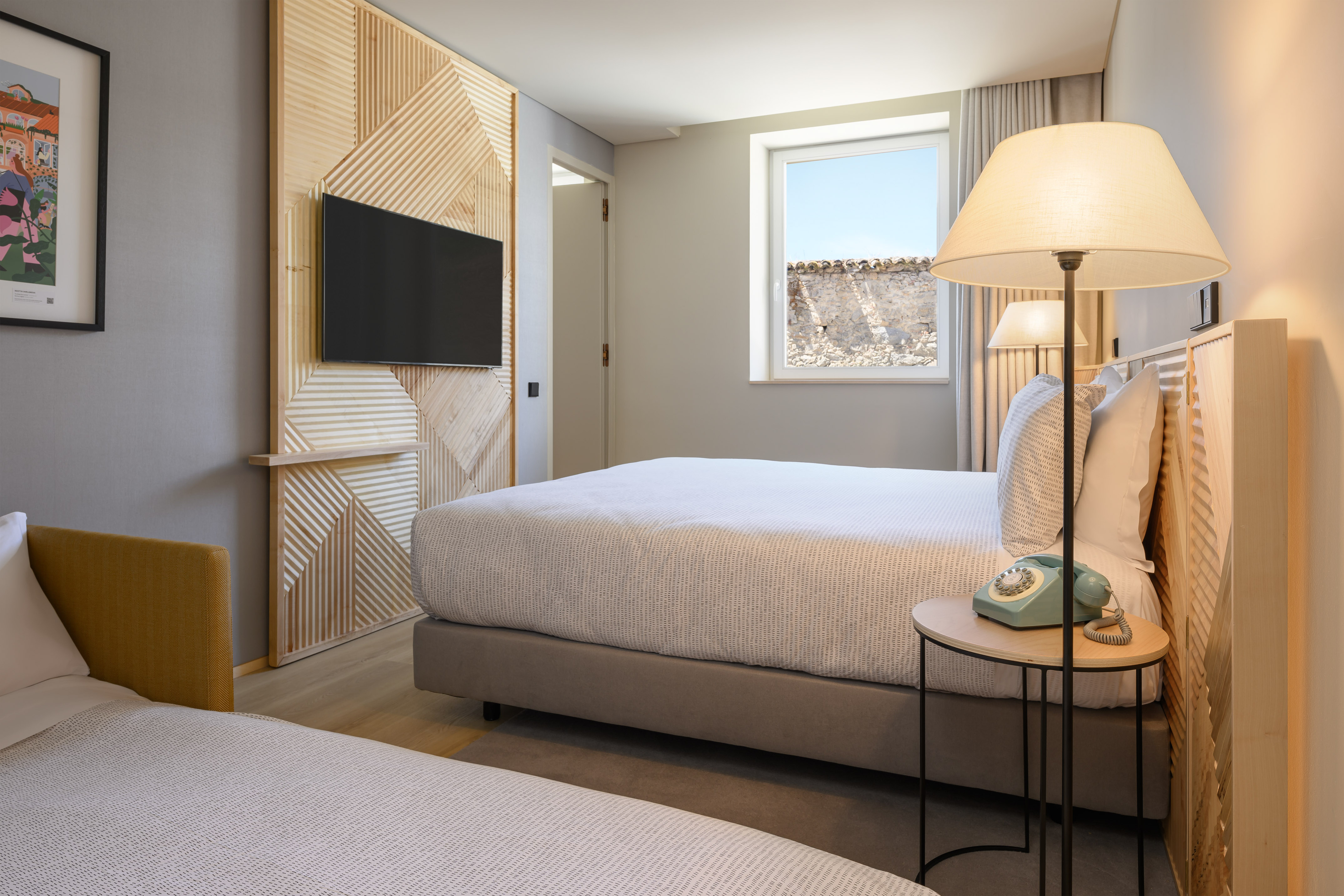 Contemporary hotel room, two beds, wooden feature wall, TV, window.