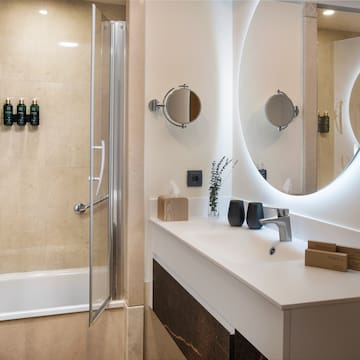a bathroom with a round mirror and a shower