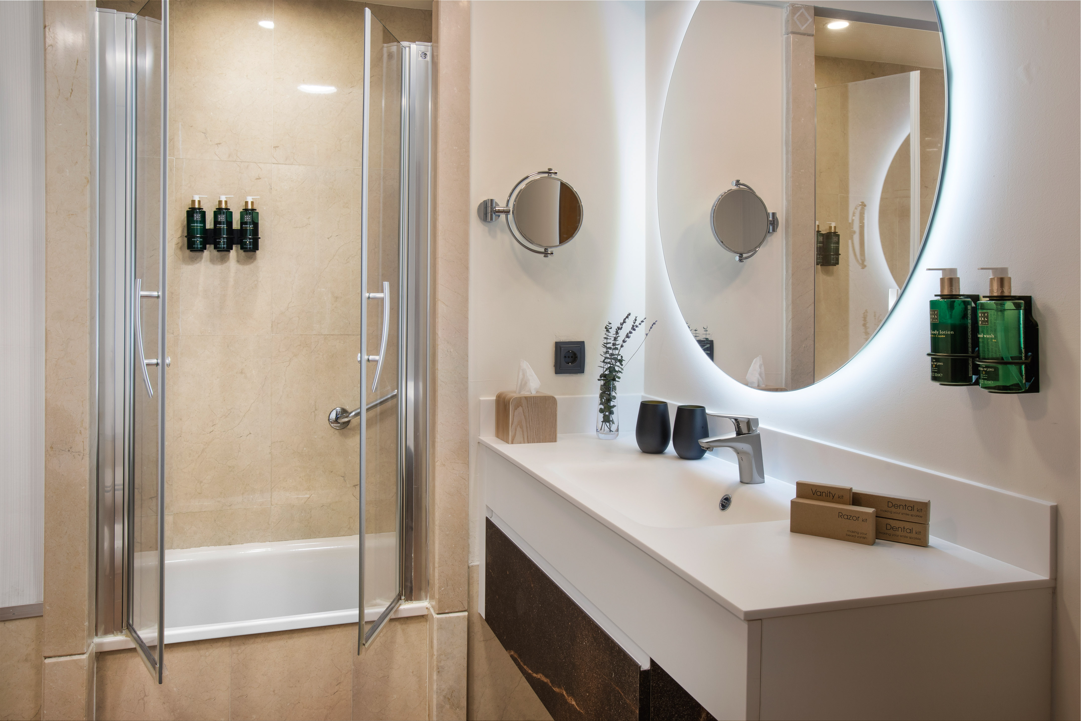 Luxury hotel bathroom with modern vanity, illuminated mirror, and shower-tub.