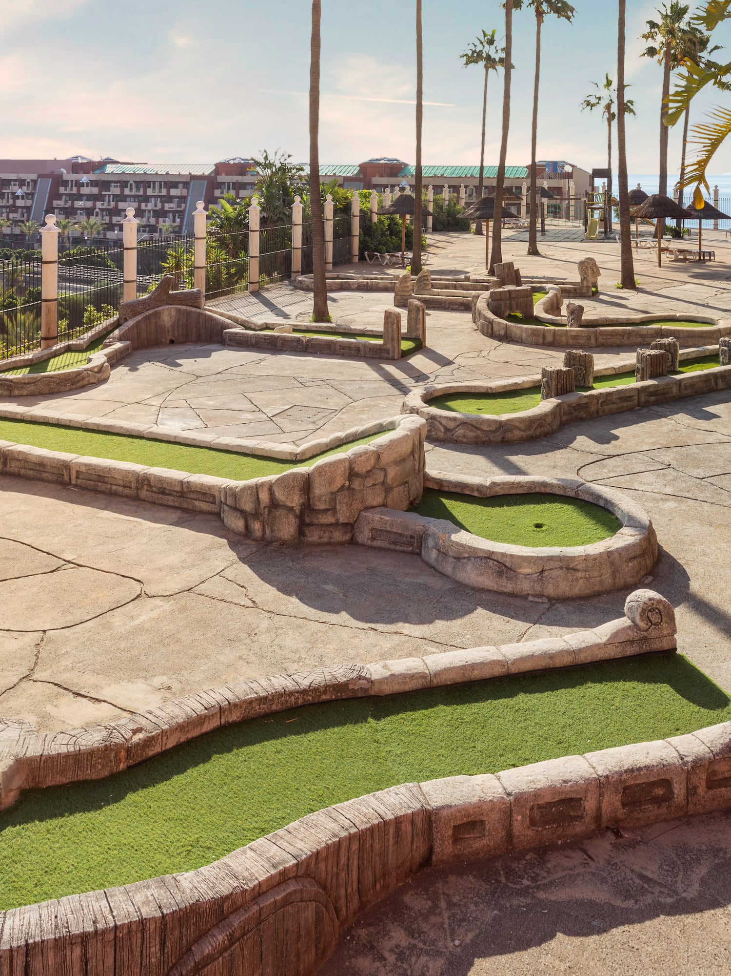 Outdoor mini-golf course with turtle obstacle, palm trees, and resort hotel.