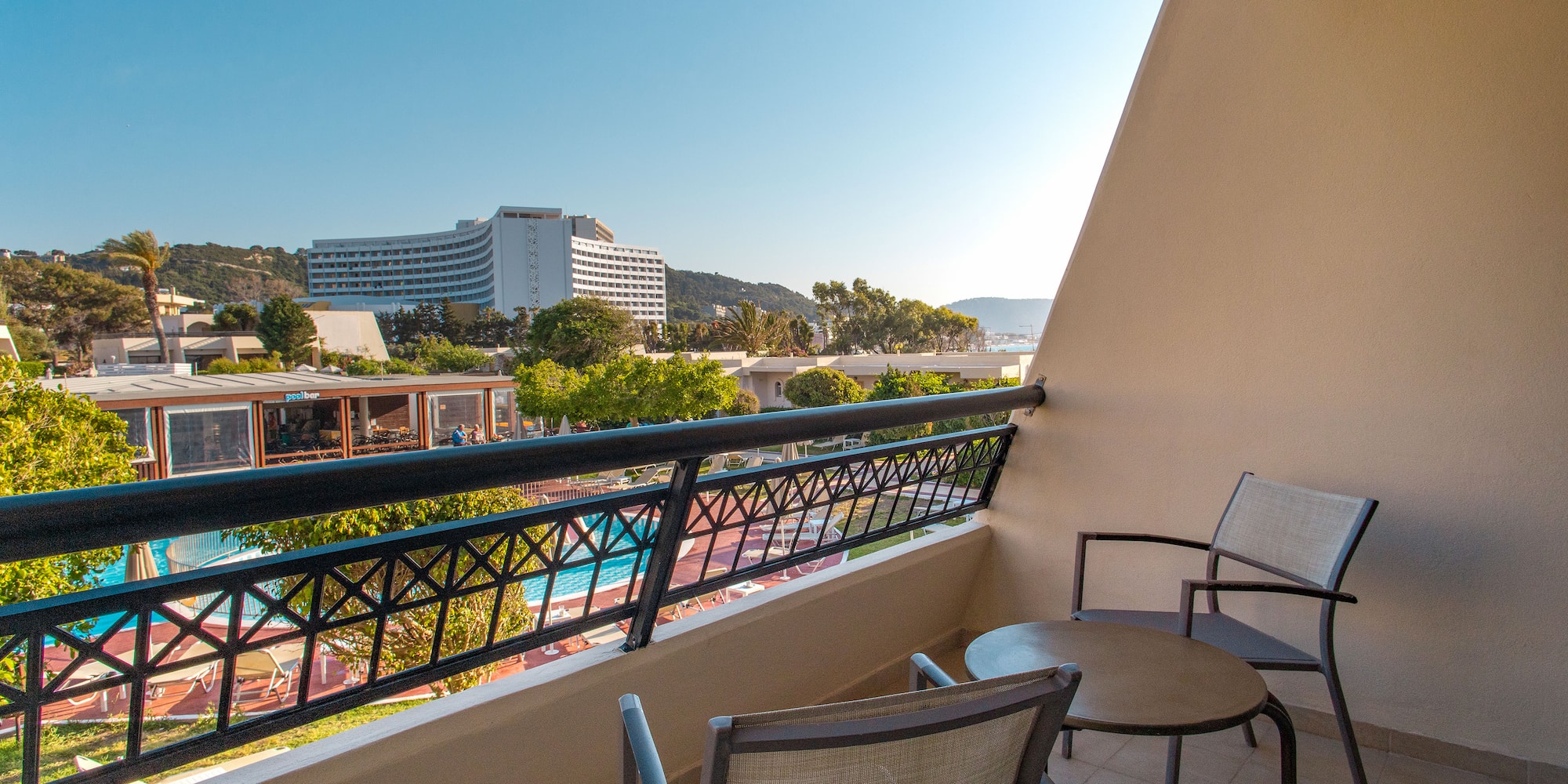 a balcony with chairs and a pool in the background