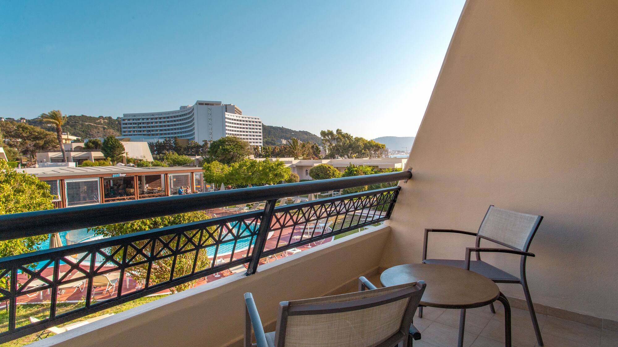 a balcony with chairs and a pool in the background