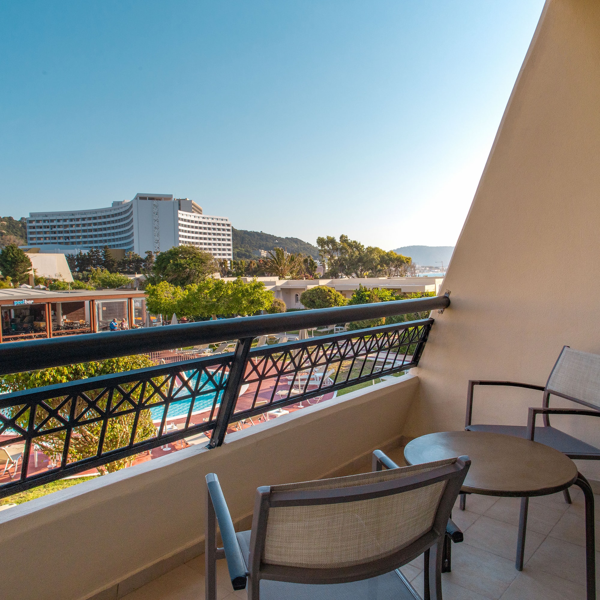 a balcony with chairs and a pool in the background