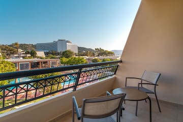 a balcony with chairs and a pool in the background