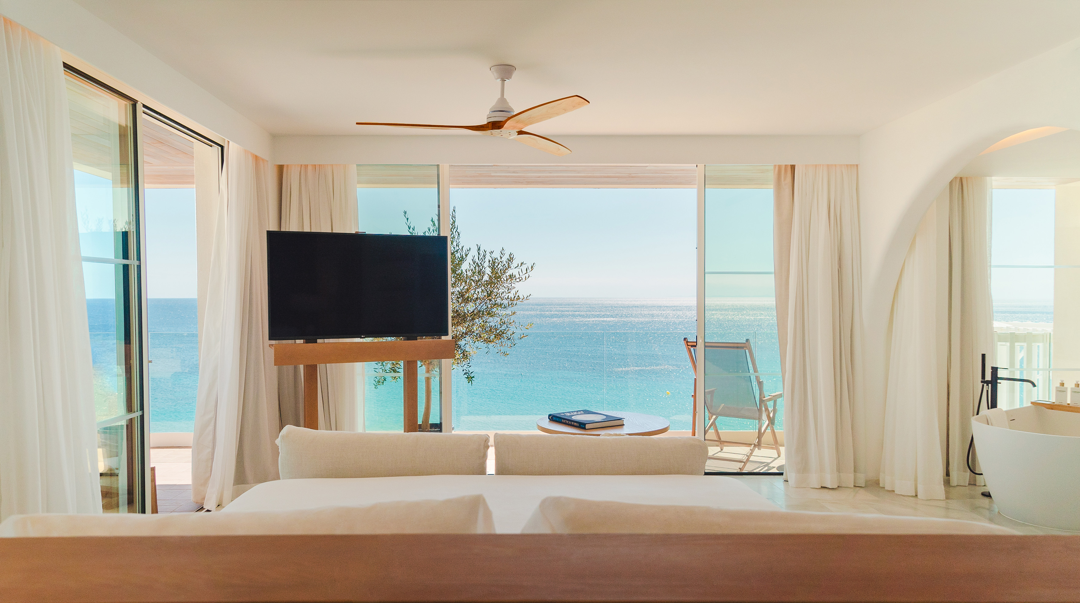 Luxury hotel suite with turquoise ocean view, balcony, and modern design.