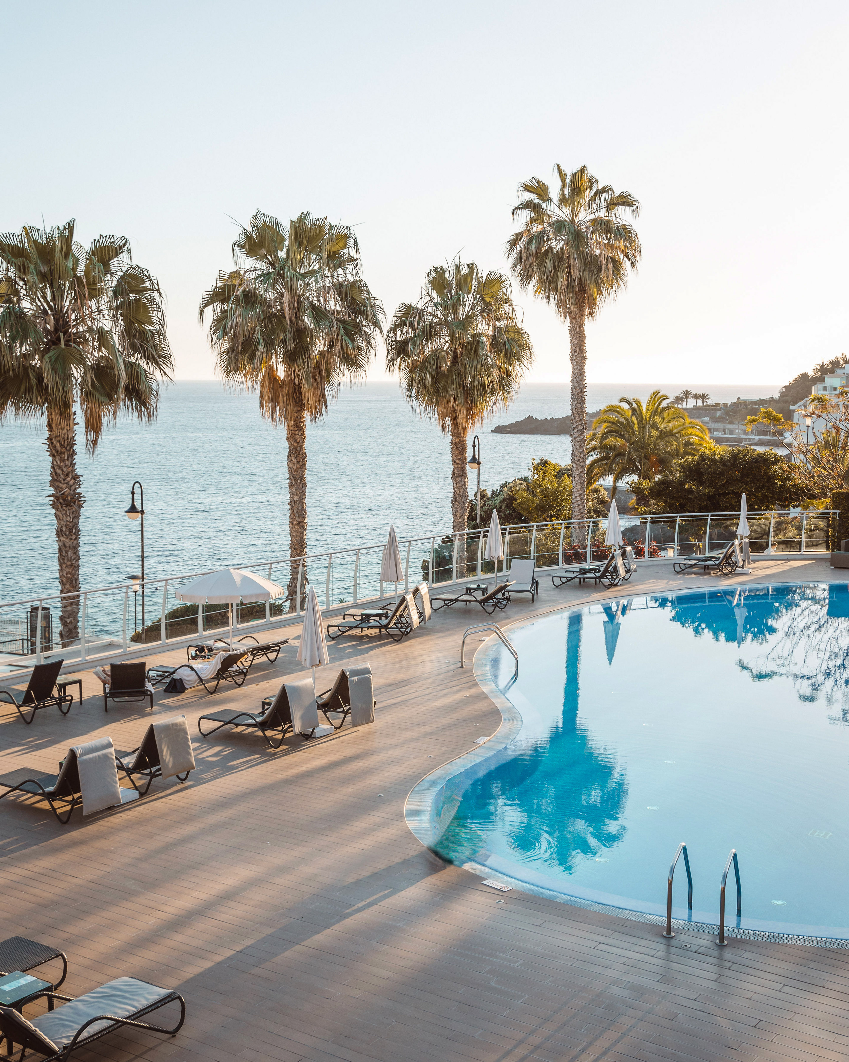 a pool with palm trees and a beach in the background
