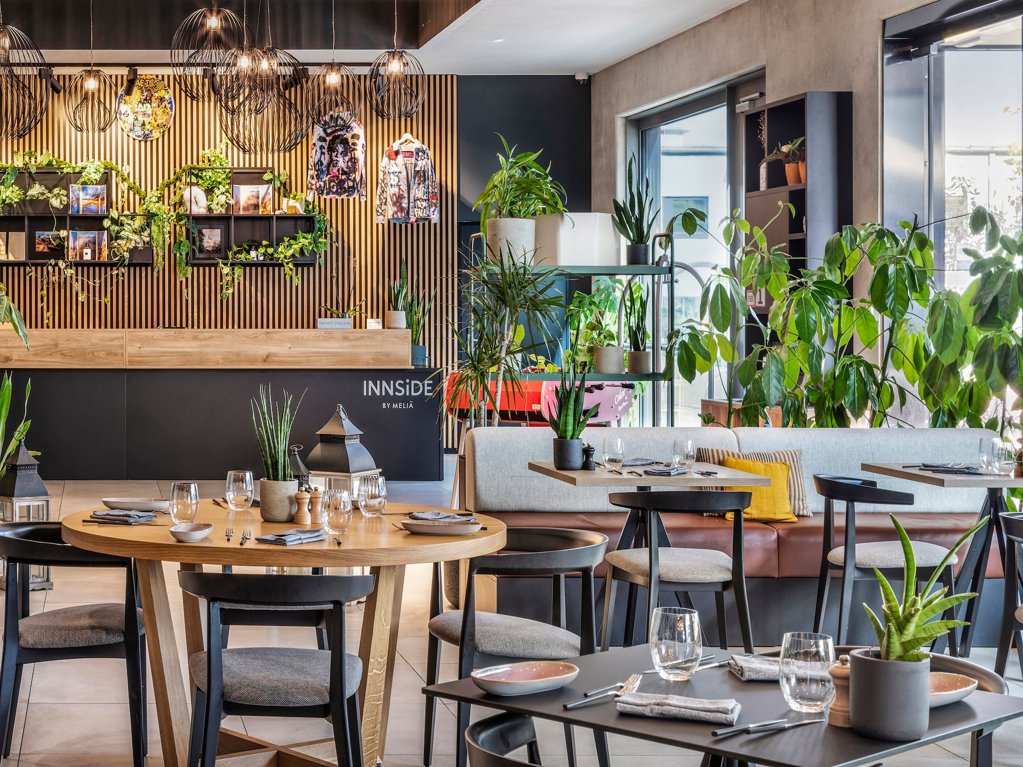 INNSiDE by Meliã modern restaurant with plants, wood slat walls, and dining tables.