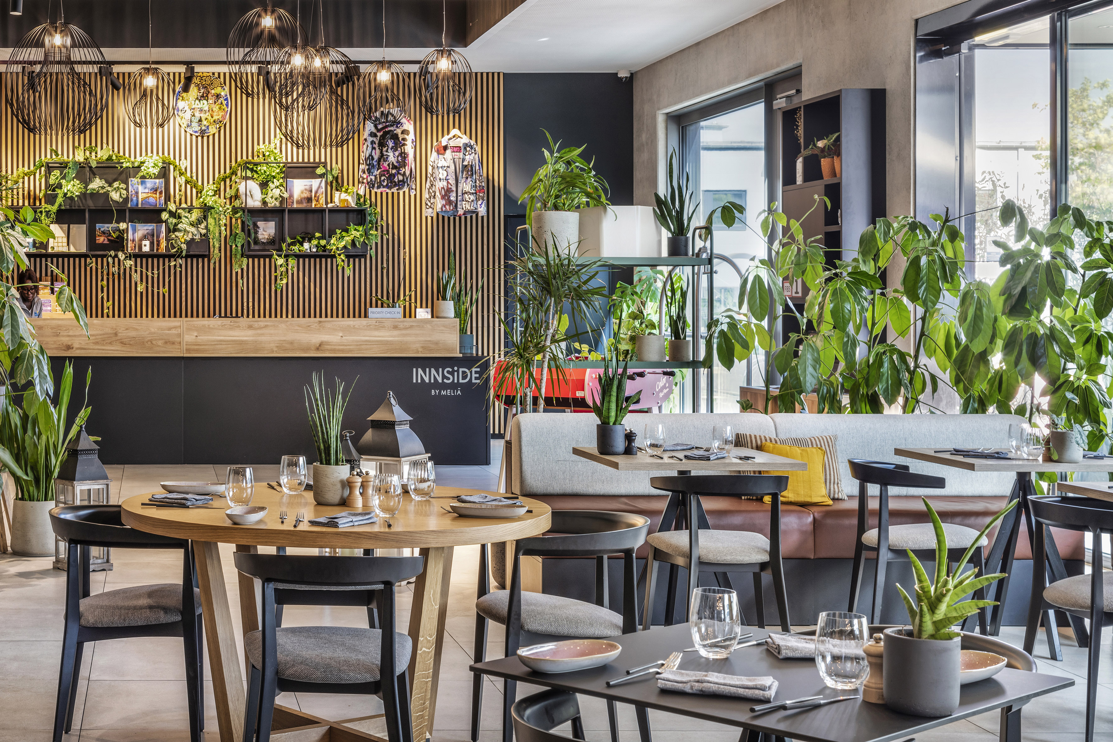 INNSiDE by Meliã modern restaurant with plants, wood slat walls, and dining tables.