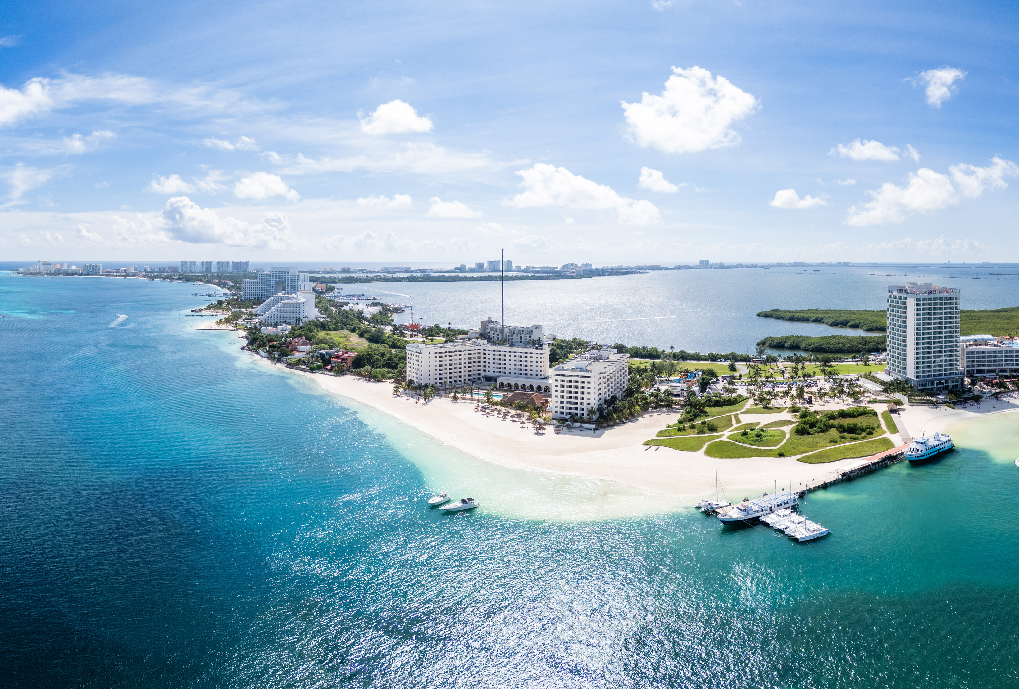 Aerial Cancun beach resorts, turquoise Caribbean sea, white sand, and boats.