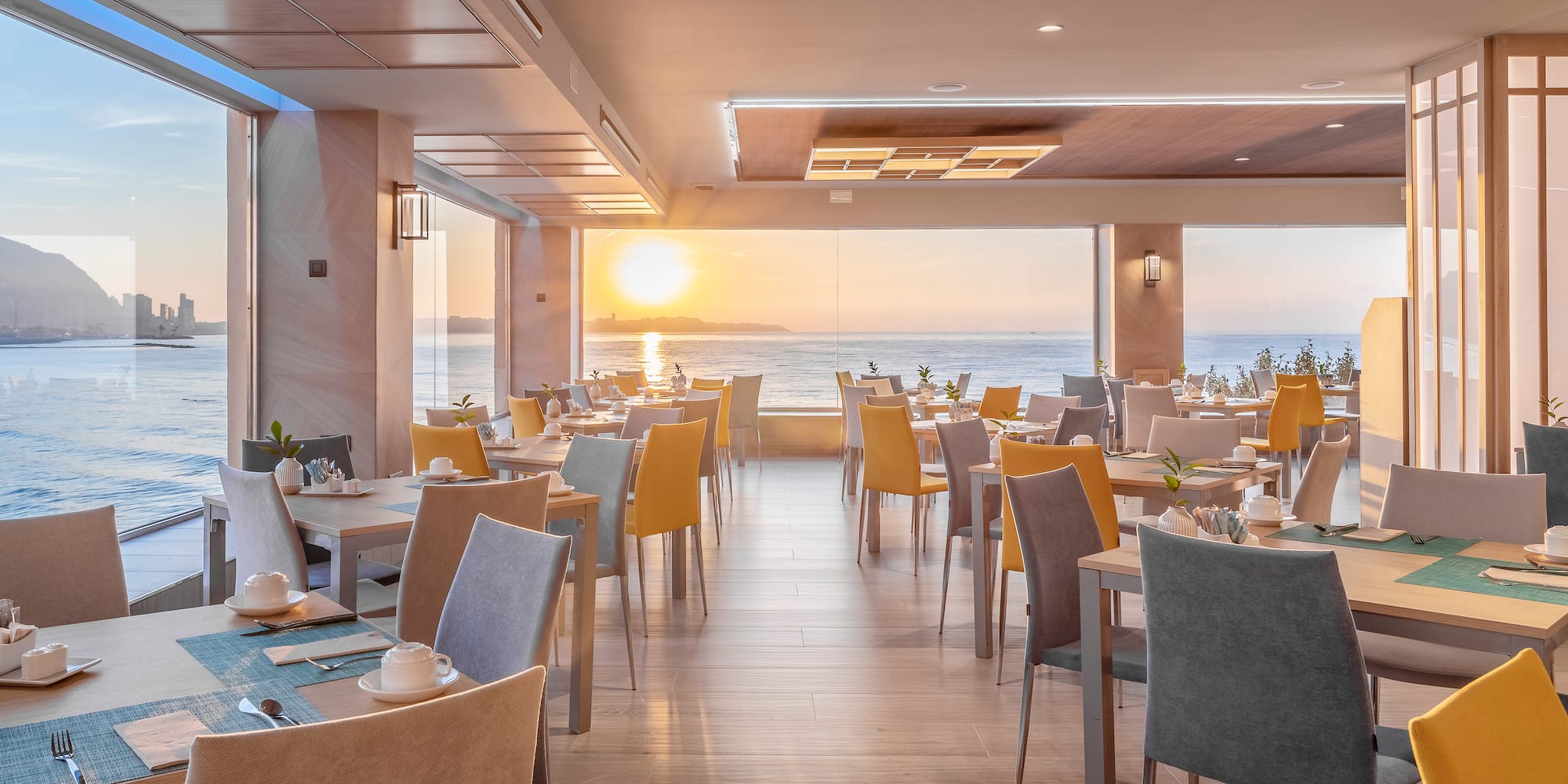 a room with tables and chairs and a view of the ocean