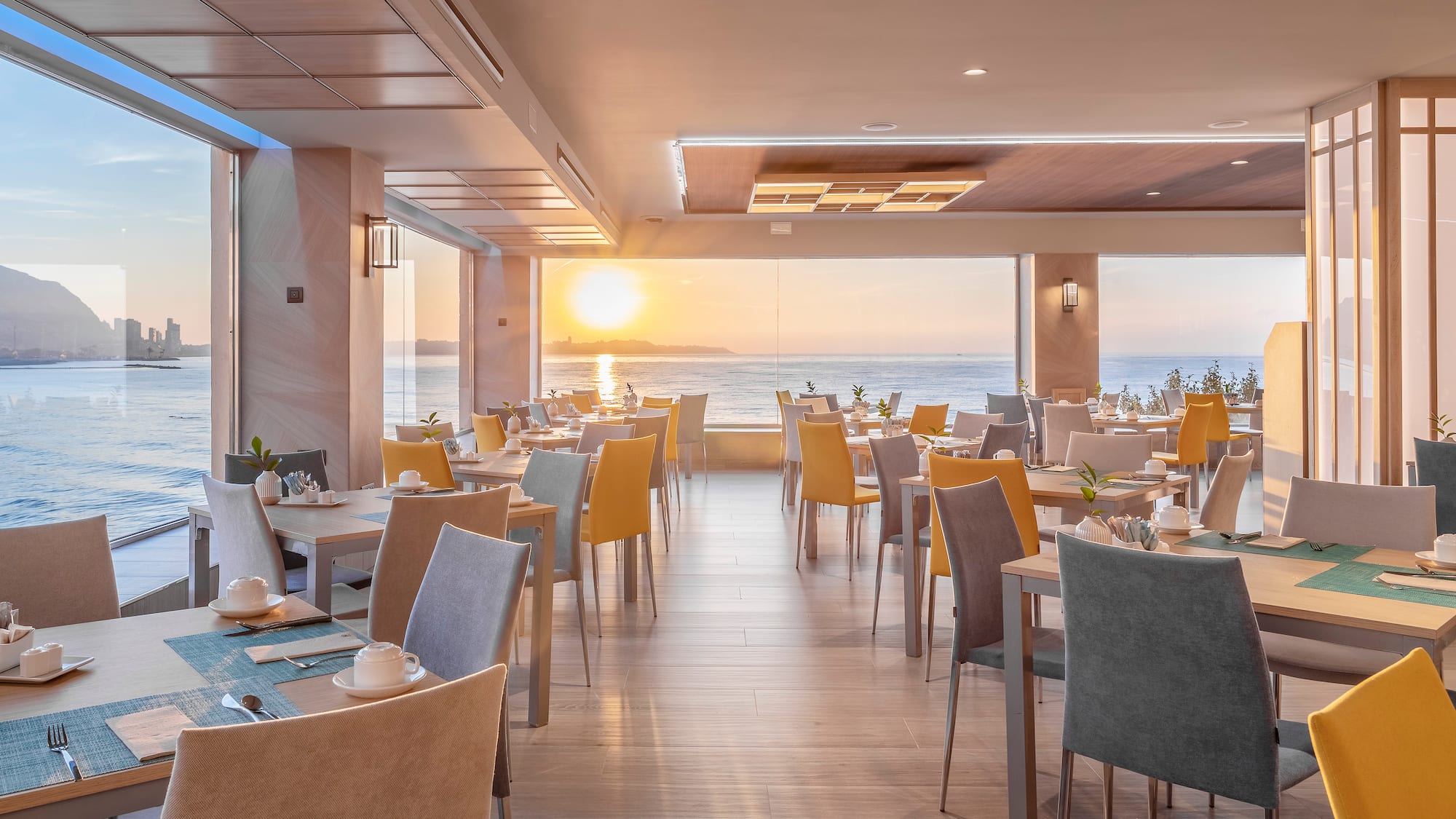 a room with tables and chairs and a view of the ocean