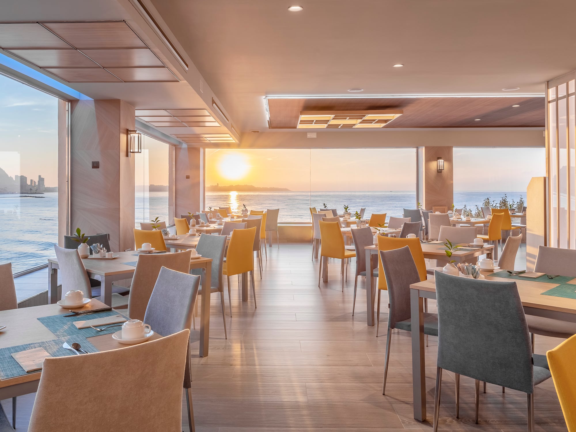 a room with tables and chairs and a view of the ocean