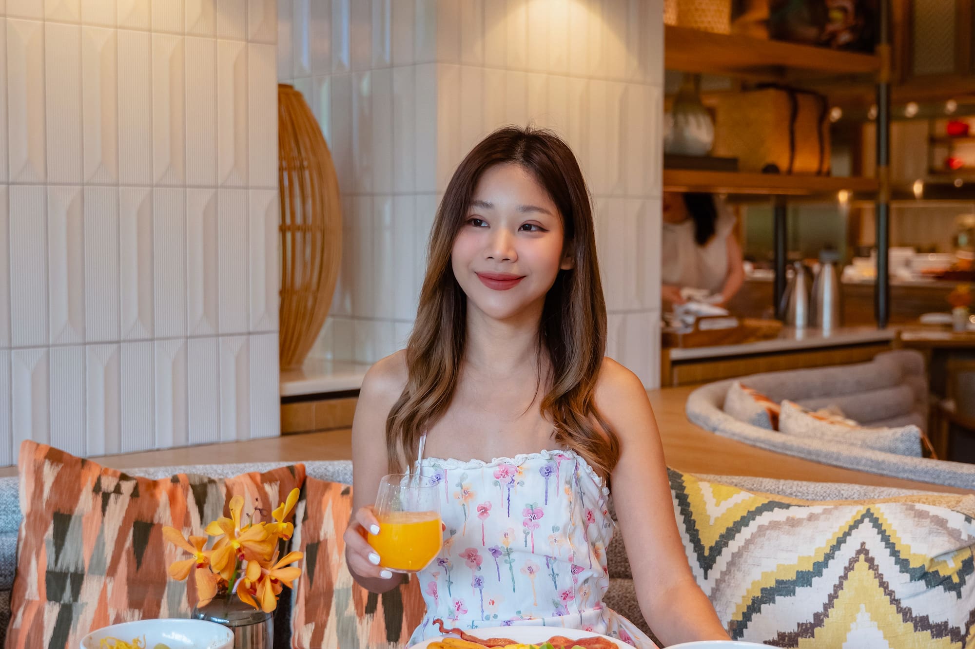 Mujer sonriente disfrutando un desayuno buffet variado en restaurante de hotel.