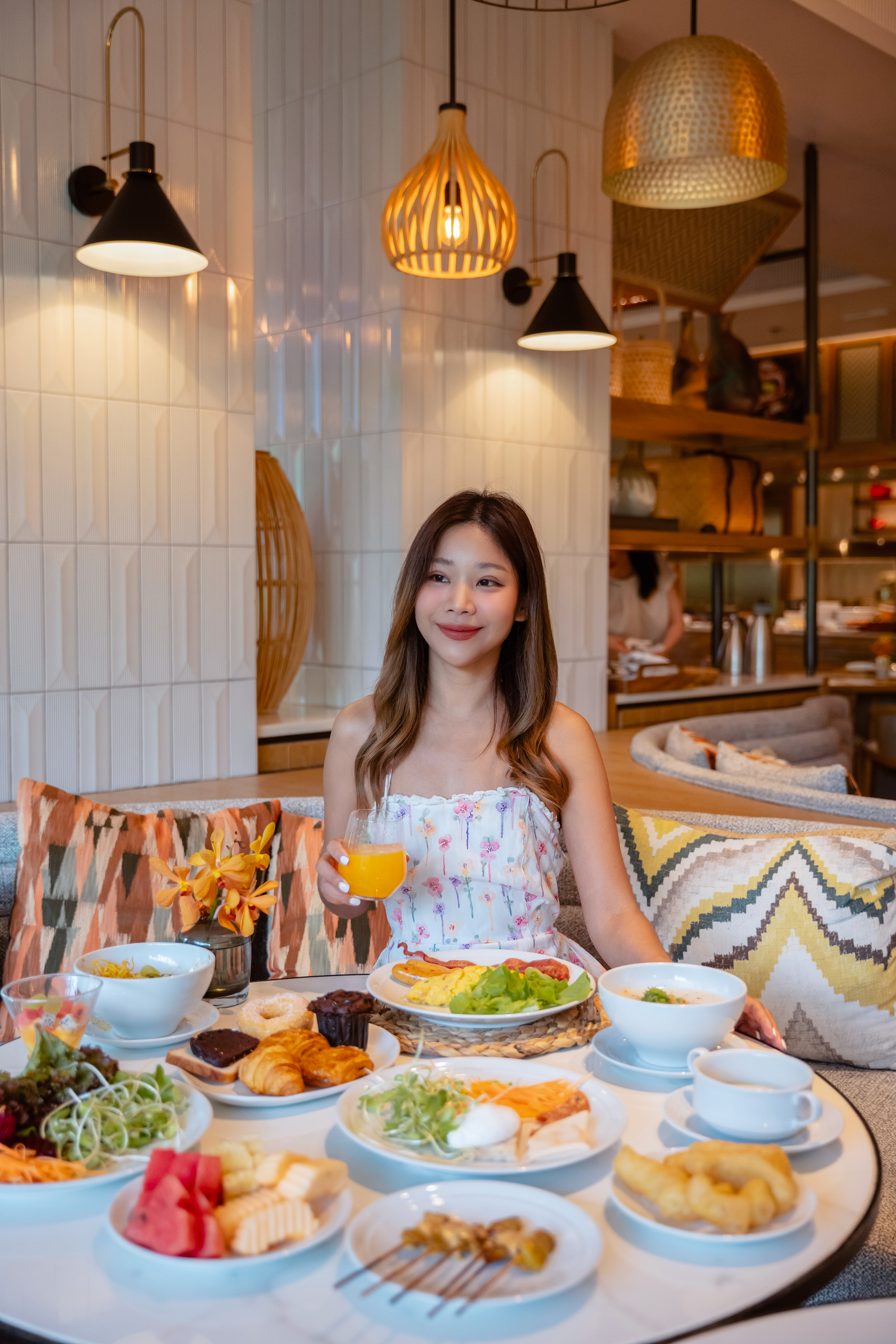 Mujer sonriente disfrutando un desayuno buffet variado en restaurante de hotel.