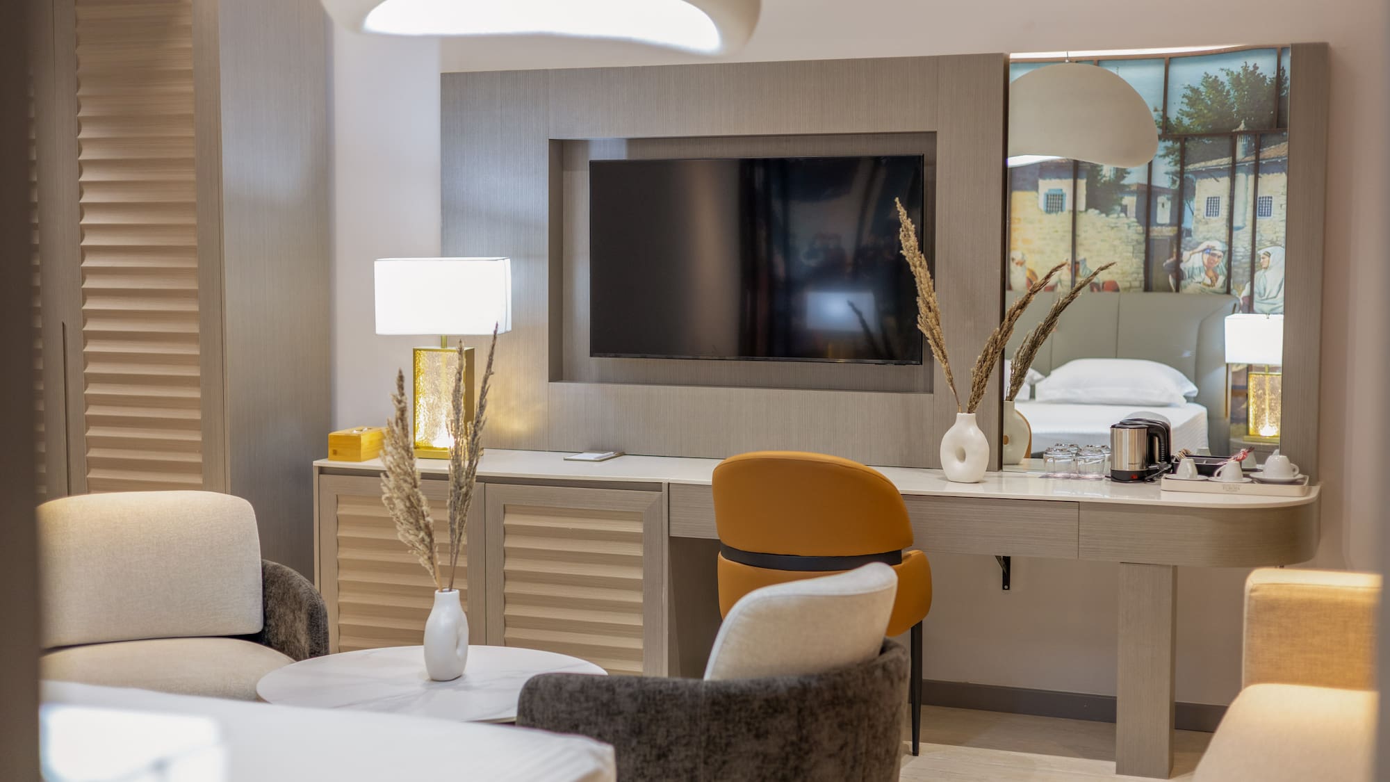 Modern hotel room with TV, desk, and stylish seating area.