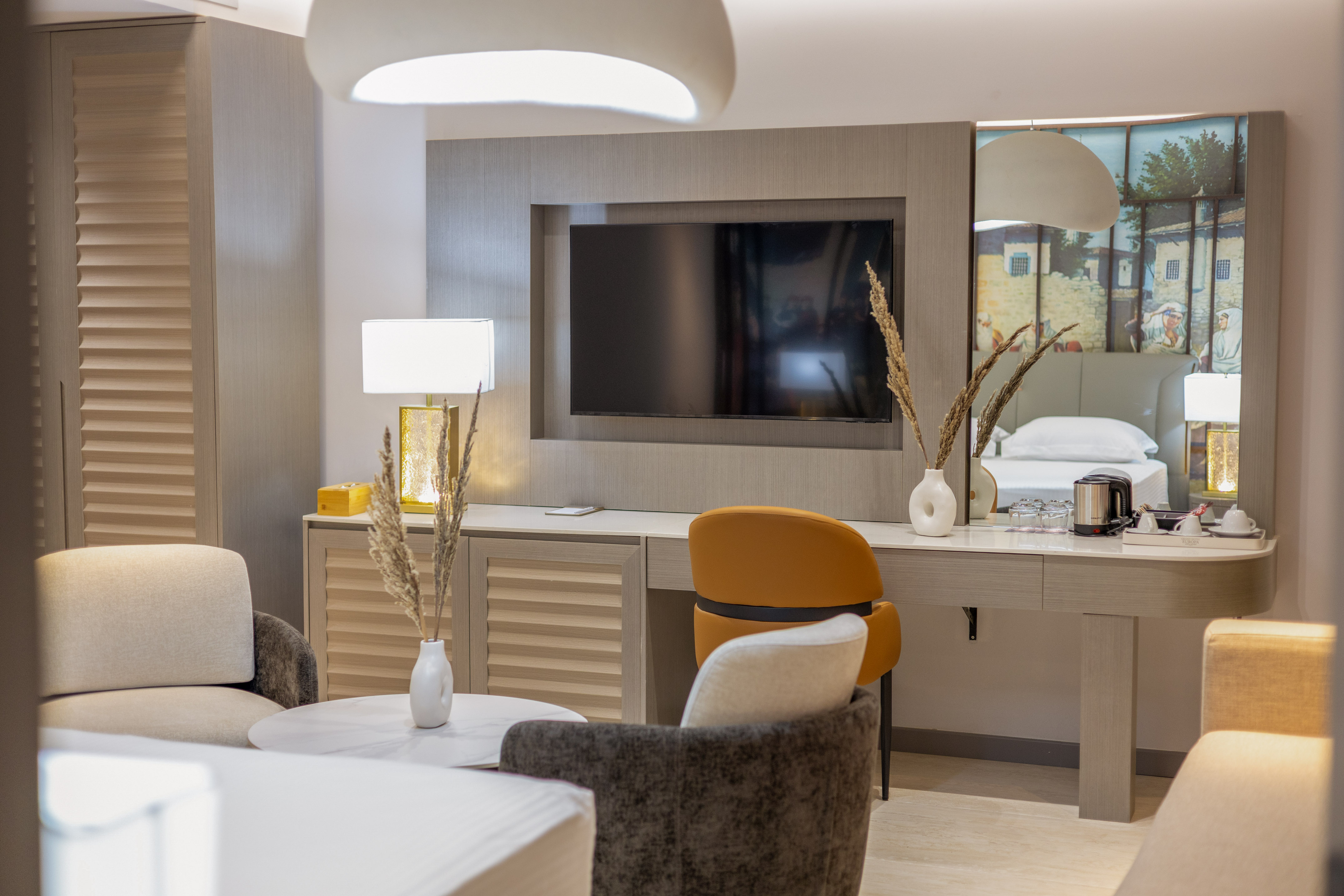 Modern hotel room with TV, desk, and stylish seating area.